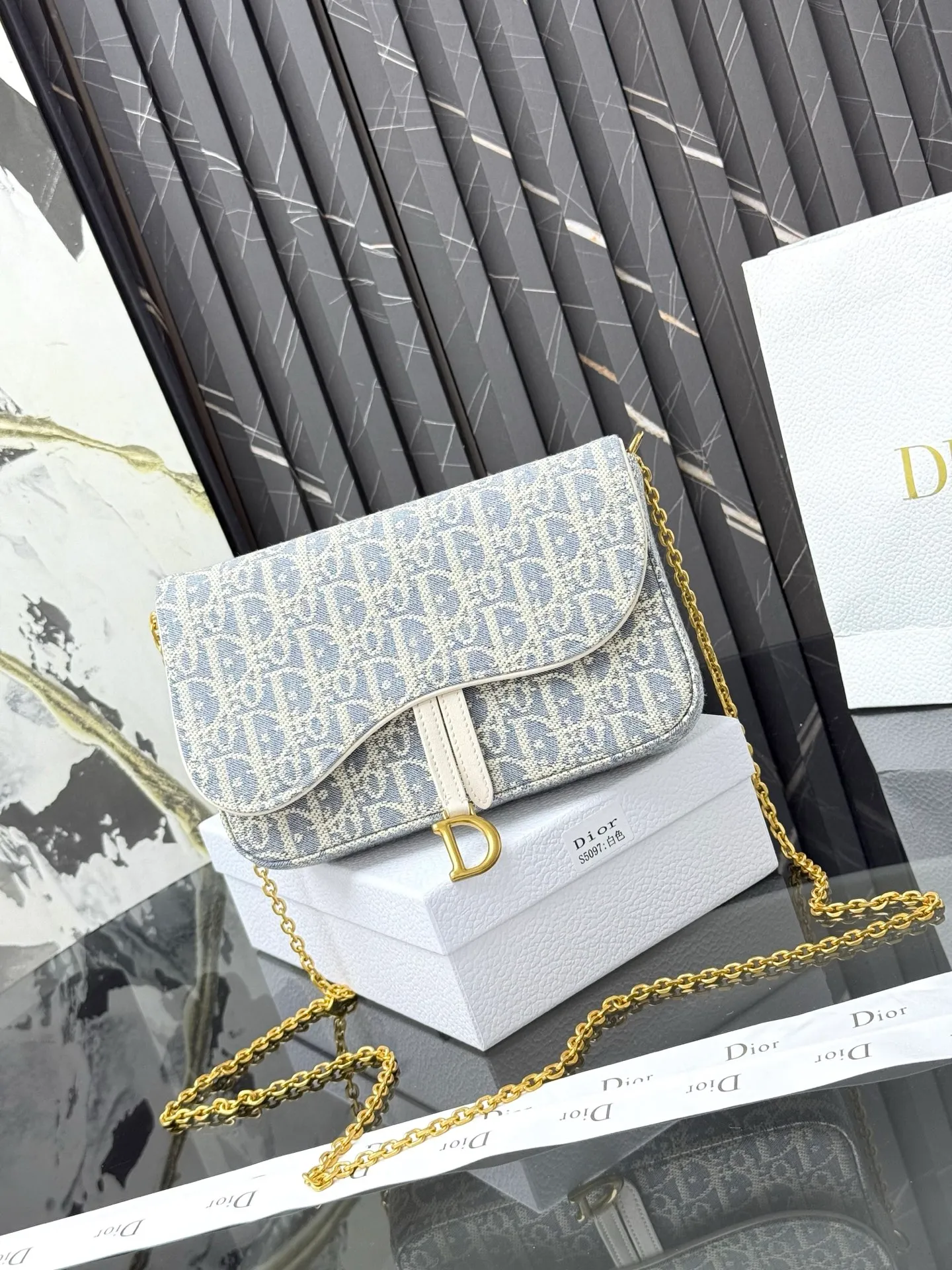 💰290💰 This saddle chain handbag has smooth and coordinated lines, making it a fashionable and practical item. Carefully crafted from blue Denim Dior Oblique jacquard fabric, the classic Dior pattern is reinterpreted with an irregular stonewash effect to highlight the fashionable style. It is paired with an asymmetric flap and a metal stirrup D-shaped pendant with antique gold finish. The spacious interior compartments can store a variety of daily essentials, and the chain makes it easy to carry on the shoulder or cross-body. Easily combines with other pieces from the saddle collection. Flap closure No.: S5907CTZQ_M928 Front stirrup D-shaped charm 1 compartment 6 card slots 1 slip pocket - No.: S5097 Dimensions: 21.5x12.5x3.7 cm (LxHxW) Can store 1 mobile phone, 1 card holder and lipstick Chain length: 118 cm Length from the top of the chain to the top of the bag: 57 cm