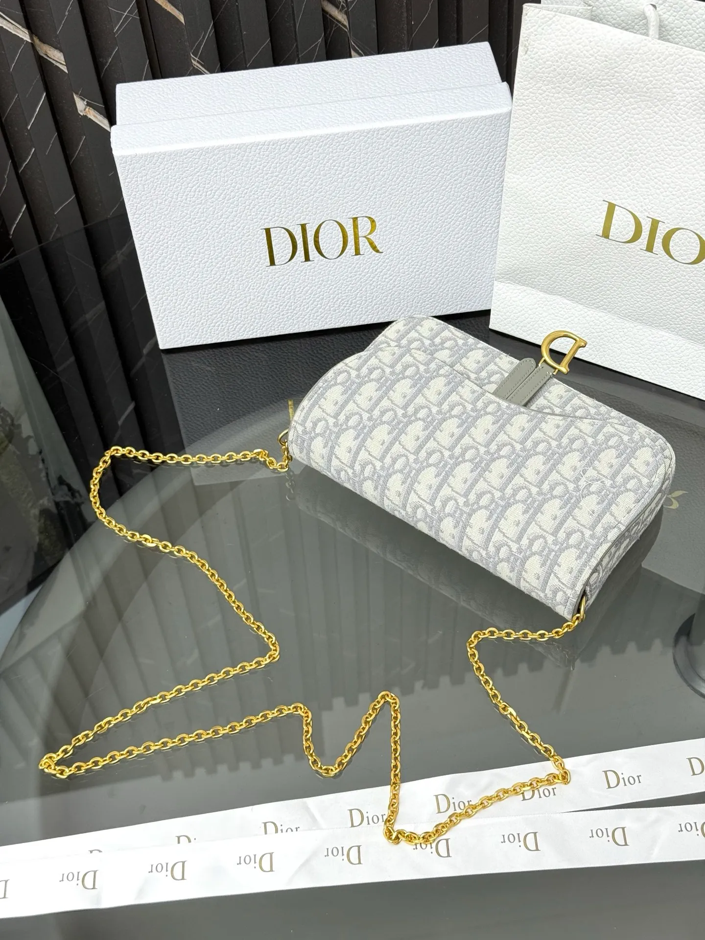 💰290💰 This saddle chain handbag has smooth and coordinated lines, making it a fashionable and practical item. Carefully crafted from blue Denim Dior Oblique jacquard fabric, the classic Dior pattern is reinterpreted with an irregular stonewash effect to highlight the fashionable style. It is paired with an asymmetric flap and a metal stirrup D-shaped pendant with antique gold finish. The spacious interior compartments can store a variety of daily essentials, and the chain makes it easy to carry on the shoulder or cross-body. Easily combines with other pieces from the saddle collection. Flap closure No.: S5907CTZQ_M928 Front stirrup D-shaped charm 1 compartment 6 card slots 1 slip pocket - No.: S5097 Dimensions: 21.5x12.5x3.7 cm (LxHxW) Can store 1 mobile phone, 1 card holder and lipstick Chain length: 118 cm Length from the top of the chain to the top of the bag: 57 cm