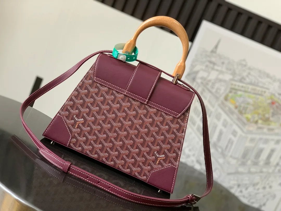 P1700 original.  The Saïgon bag is one of the iconic pieces of the House of Goyard, embodying all the characteristic elements of the brand's boxmaking craftsmanship, such as wood, strips, leather corners and tacks. The Saigon Small Bag features a structured design and a removable shoulder strap for a chic and elegant look.  20 cm x 12 cm x 28 cm 🔎LAR 020186-maroon