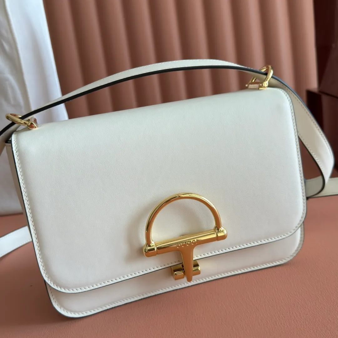 p1640. 💋💋💋【With full set of original counter packaging】2025 autumn and winter series, the Gucci Siena series small shoulder bag continues the evolution of the iconic element of Gucci's classic horsebit. Crafted from fine glossy leather, this shoulder bag has a structured shape and a half-horsebit buckle design from the 1970s. Finished with gold-tone hardware, the interior is lined with three levels of gusseting and a zipped pocket. Black fine glossy leather Gold-tone hardware Black leather lining Interior: 3-level fastening and 1 zipped pocket Shoulder straps: Height: 23cm – 25cm; Length: 127cm Half-horsebit snap fastener Ident: 846705. Dimensions: 22.5cm (width) x 14cm (height) x 8cm (depth) Weight: approx. 0.7kg Color: White full leather. Made in Italy