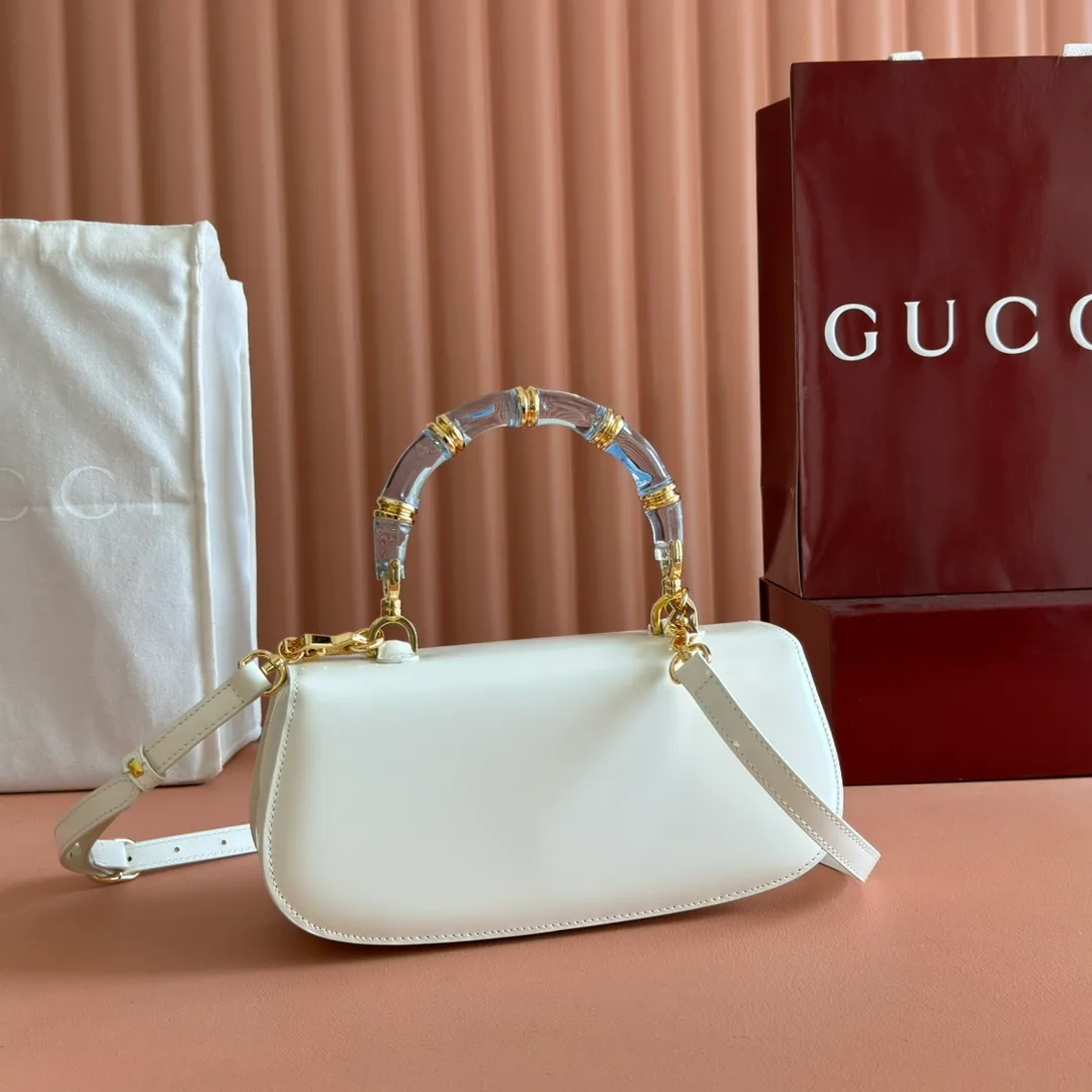 p1680. 💋💋💋 Equipped with full counter packaging [New Product] This small handbag reinterprets the iconic bamboo-shaped accessories with resin and brass details, adding another dazzling masterpiece to the 2025 spring and summer series. The Gucci Bamboo Diva tote adds a pop of color to any look. White glossy buffed leather Resin and brass bamboo hardware Three-level articulated compartments White leather lining Interior: One zippered pocket and a mirror with removable pocket Handle height 10cm Removable and adjustable leather shoulder strap (50cm high); length adjustable between 100cm and 116cm Bamboo lock Model number: 827750 Dimensions: 26.6cm (width) x 13cm (h) x 8 cm (depth) Weight: about 0.9 kg Color: white full leather/original leather. Made in Italy