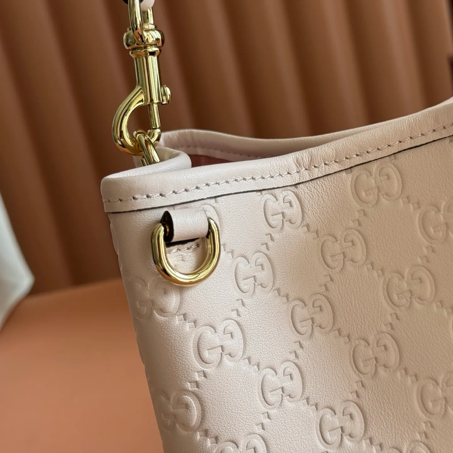 p1140. 💋💋💋【With full set of original counter packaging】GG Emblem series reinterprets the brand's timeless elegance and exquisite craftsmanship. Lined in webbed cotton, this bucket bag features an internal compartment for added functionality. Apricot pink GG printed embossed calf leather Light gold tone hardware Taupe cotton and linen lining Additional D-ring for attaching removable items Interior: two compartments and a central snap compartment Top handle with hook closure (height: 14 cm) Removable and adjustable calf leather shoulder strap (height: 52 cm - 57.5 cm; length: 107 cm - 114 cm) Magnetic snap closure Ident No.: 815118. Dimensions: 19cm (W) x 18cm (H) x 11cm (D) Weight: Approx. 0.45kg Color: Apricot Pink/Embossed. Made in Italy