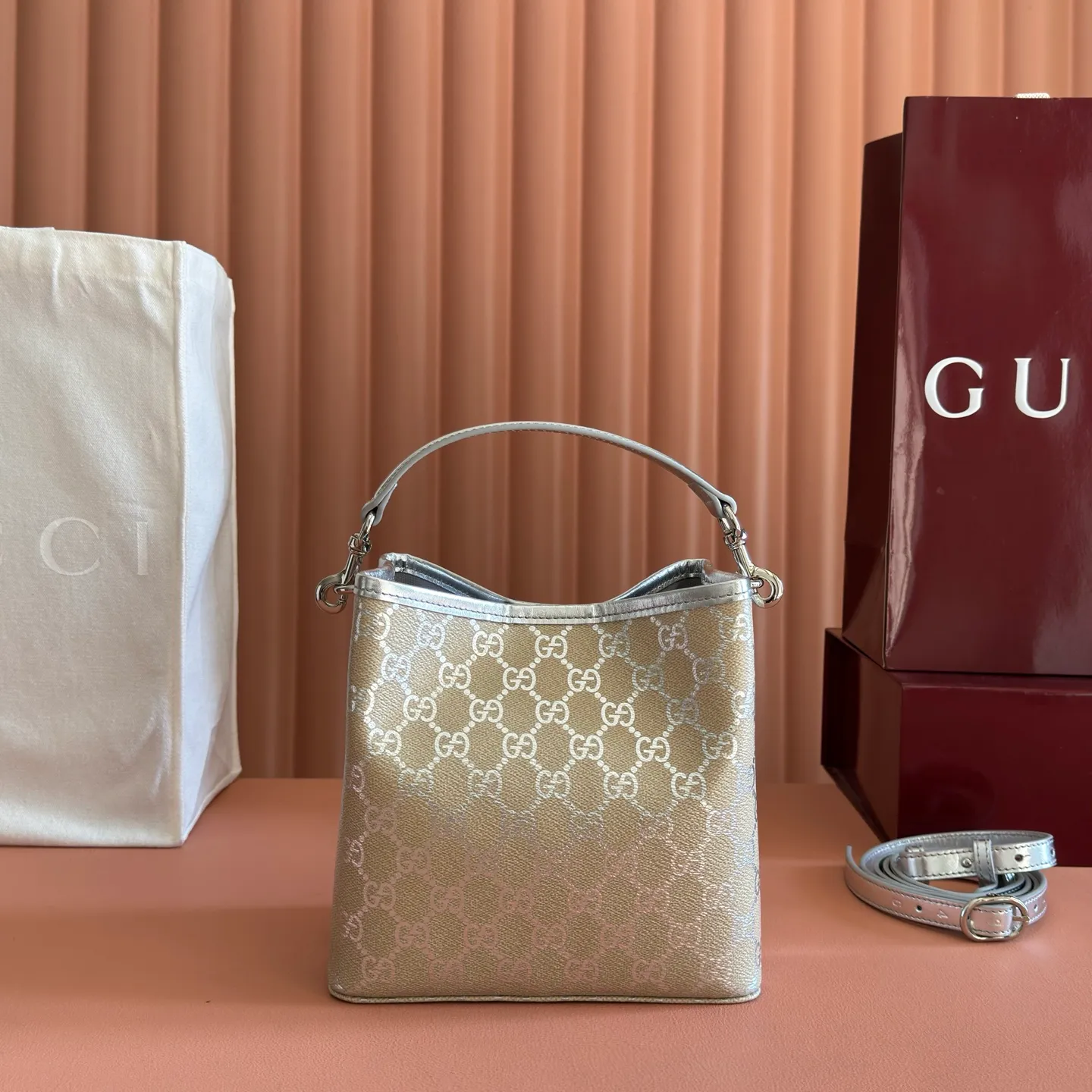 p940💋💋💋【Equipped with full set of original packaging at the counter】The GG Emblem series reinterprets the brand's enduring elegance and exquisite craftsmanship. It uses metallic styles to create a new interpretation of the iconic GG pattern, and is paired with metallic leather piping to complete the overall design. Light beige and silver metallic laminated-effect GG monogram coated fabric Silver metallic leather trim Silver-toned hardware Light gray cotton and linen lining Additional D-ring for attaching detachable items Interior: Two compartments and a central snap-stud compartment Top handle with hook closure (Height: 14cm) Removable and adjustable leather shoulder strap (Height: 52cm - 57.5cm; Length: 107cm - 114cm) Magnetic snap closure Model: 815118. Dimensions: 19cm (W) x 18cm (H) x 11cm (D) Weight: approx. 0.45kg Colour: Light Beige/Silver. Made in Italy