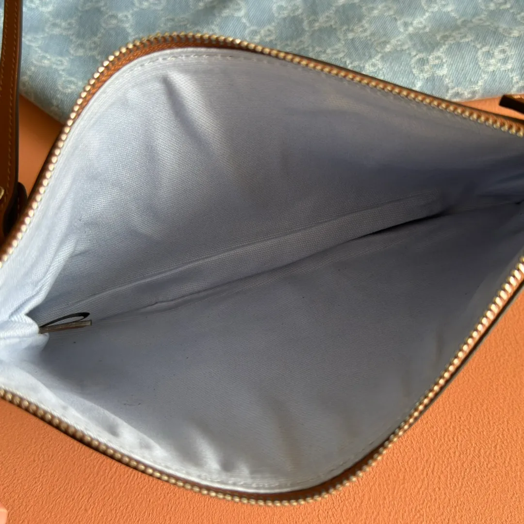 Pre-order 💋💋💋【Equipped with counter gift bag】The Gucci Totissima series combines the word "tote" with the superlative word "issima" in Italian, highlighting the practical function and timeless background of this handbag. This medium tote bag comes with a removable clutch. Blue GG denim Brown leather trim with contrasting stitching Blue cotton and linen lining Detachable clutch: 21.5 cm (W) x 12.5 cm (H) Top handle (21 cm H) Model: 820481. Dimensions: 30.5cm (width) x 28cm (height) x 27cm (depth) Color: Gray denim/original leather. Weight: approx. 0.6kg Made in Italy