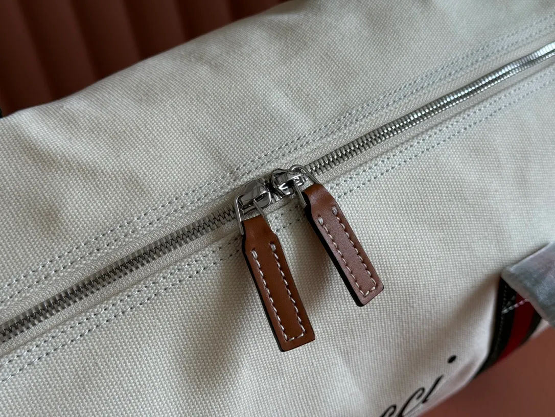 p1060. 💋💋💋"With a complete set of original counter gift bag packaging"💕[New Product] With the theme of freedom, vitality and community, the 2025 spring and summer series has newly presented a variety of travel items and men's bags, adding more fun to travel and exploration. This canvas travel bag features embellished stitching at the top, tonal leather piping and a 'Gucci Made in Italy' badge printed on the front. Off-white canvas Off-white leather trim "Gucci Made in Italy" and badge print Red and blue web Interior: 1 side handle Handle height: 24 cm Adjustable web canvas shoulder strap (55 cm high); length adjustable from 82 cm to 138 cm Zip closure Ident: 816866. Dimensions: 54cm (W) x 24cm (H) x 24cm (D) Weight: Approx. 0.985kg Colour: Off-white canvas. Made in Italy