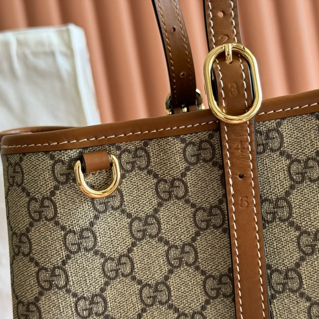 p980. 💋💋💋"With full set of original counter packaging" [New product] GG Emblem series reinterprets the brand's timeless elegance and exquisite craftsmanship. Inspired by the equestrian world, this tote bag features an adjustable top handle with numbered eyelets. New GG monogram coated fabric in beige and dark brown Orange leather trim with contrast stitching Light gold tone hardware Red and green webbing cotton lining The bag pictured is sold separately and does not come with the bag charm. Also features D-ring for hanging removable items Adjustable handle with numbered eyelets (height: 21.5 cm - 31.5 cm) Interior: two compartments and one central zipped compartment Magnetic snap closure Ident.: 815213. Dimensions: 38cm (width) x 25cm (height) x 15cm (depth) Weight: about 0.85kg Color: brown PVC/original leather. Made in Italy