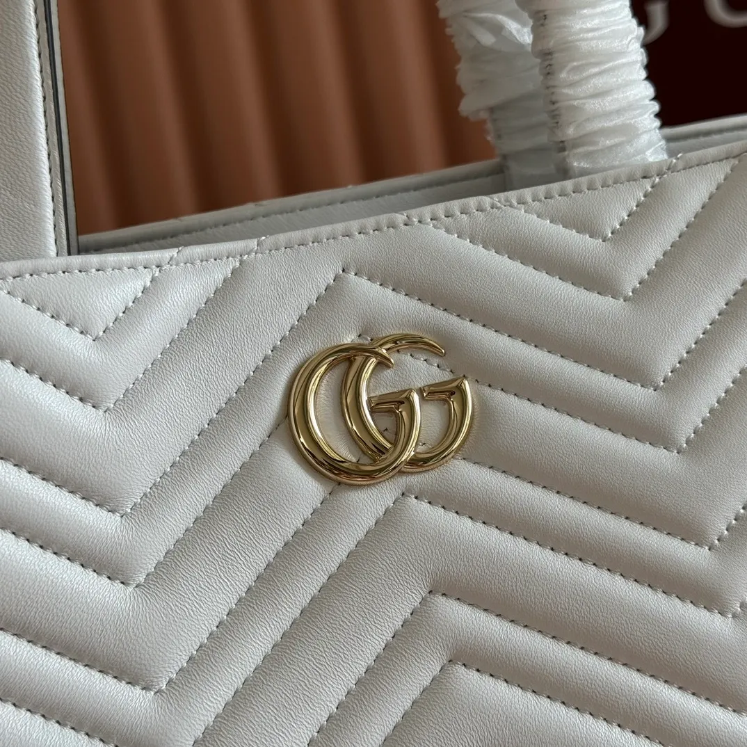 p1400. 💋💋💋 Comes with a complete set of original counter packaging [New product] This tote bag injects novel charm into the GG Marmont series with a new silhouette in the 2025 autumn and winter series. It can transform from a structural tote bag to a soft-lined bucket bag. The shape is paired with top handles and chain shoulder straps, presenting a variety of fashion styling options. Black V-shaped quilted sheepskin. Light gold-tone hardware. Gucci ankara red viscose lining. Double G. Interior: Zip pocket. Handle drop 14 cm. Shoulder strap drop 53 cm (bag closed: 48 cm). Ident.: 847387. Dimensions: 28cm (bottom width) x 39cm (top width) x 24cm (height) x 16cm (depth) Weight: approx. 0.7kg Color: White sheepskin. Made in Italy