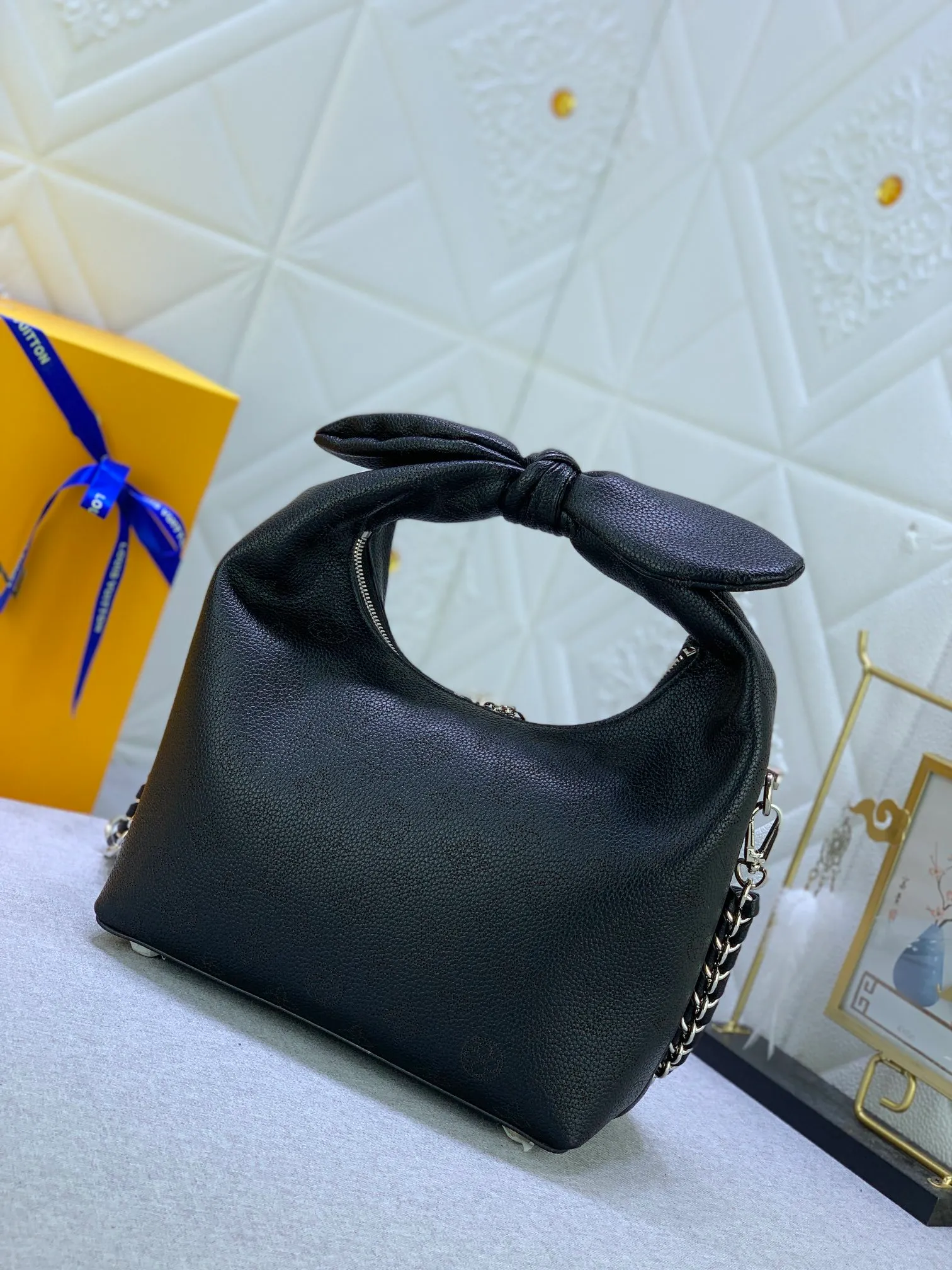 All categories Official website "Brand Women's Bags" Women's Bags 💙 LV Why Knot small handbag is made of Louis Vuitton's iconic Monogram engraved and perforated cow leather, combined with a knot-shaped handle, exuding a gentle style and modern atmosphere. Functional design holds everyday essentials such as a cell phone, wallet, keys, and sunglasses, and the removable woven leather chain allows for easy shoulder wear.