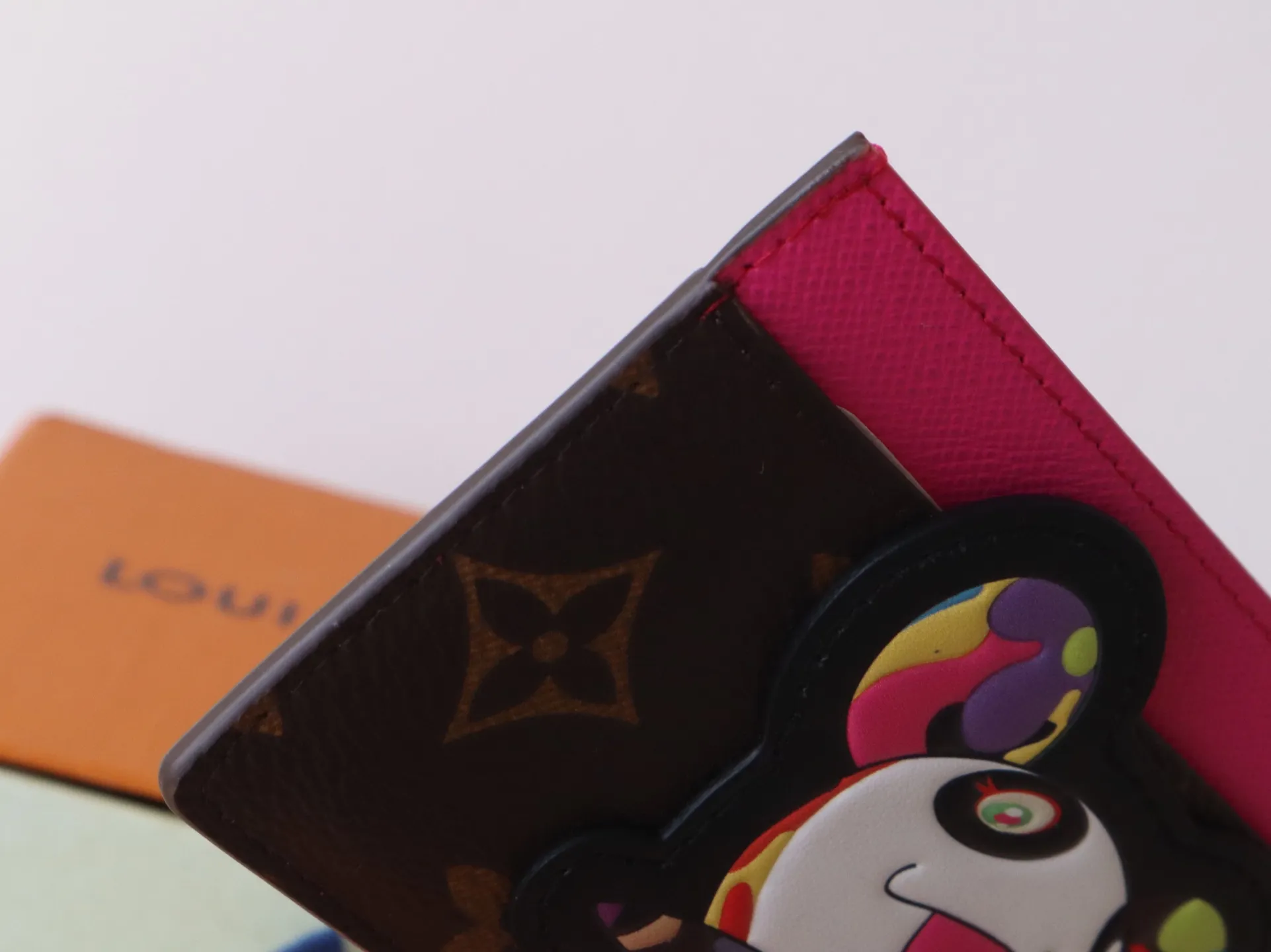 M13439 Card Holder🌟P280 LV x TM Business Card Holder This essential business card holder is reinterpreted with lively details from the Louis Vuitton x Murakami collaboration series, full of joy. The brand's classic Monogram pattern is covered with a bright panda pattern created by Japanese artists, which complements each other with a bright touch of pink on the top. Crafted from coated canvas, the business card holder has a stylish cut and multiple compartments to keep everyday essentials such as business cards and receipts organized.  11 x 7 x 0.5 cm