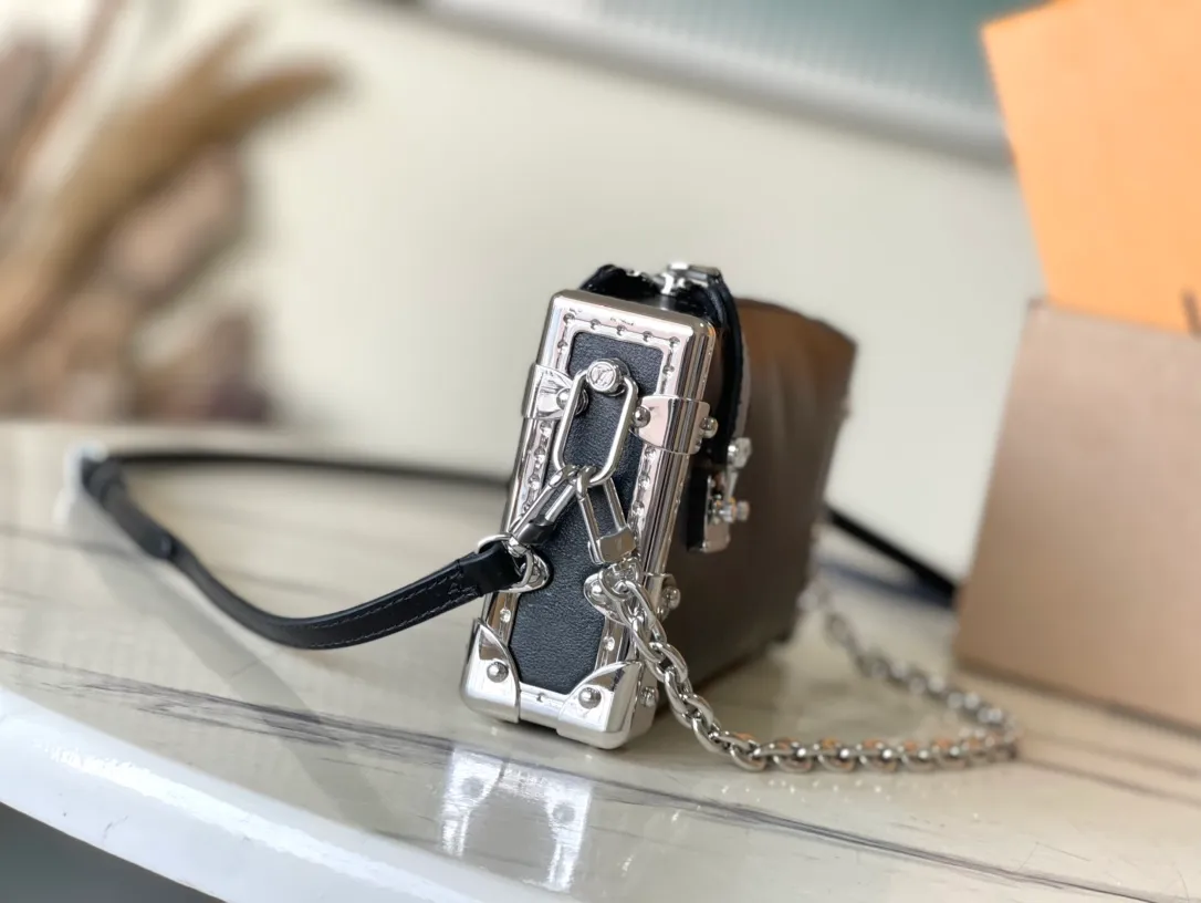 💰1420 (first-grain leather) Top-quality original order M25445 This Slim Trunk handbag draws inspiration from Louis Vuitton’s traditional hard trunk. The soft cow leather is integrated with rivet frames and metal S-lock locks, highlighting the avant-garde rock style. The shiny chain and adjustable leather shoulder strap are both detachable, providing a variety of carrying options. Dimensions: 23 × 12 × 4 cm