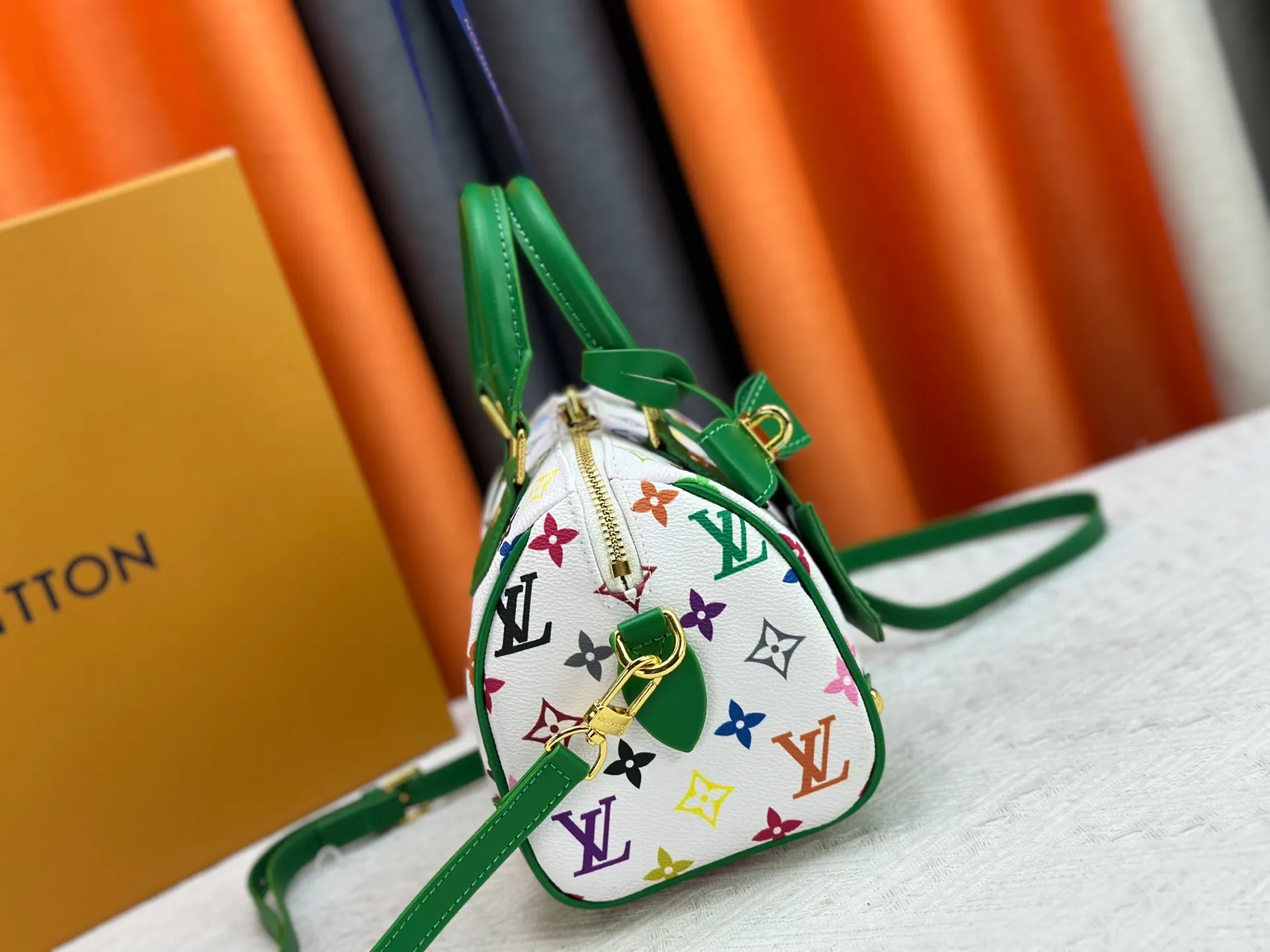 P260 upgraded original M58953 M46234 M46222 Speedy Bandoulière 20 handbag is made of soft coated canvas, and the full-length Monogram pattern is traced in colorful rainbow tones, highlighting the smart style of the Louis Vuitton x Murakami reissue series. The Toron handle and detachable shoulder strap are constructed of cow leather, the metal corners recall classic luggage elements, and the bow-shaped key bag and padlock add brand touches. Dimensions: 20.5 x 13.5 x 12.0 cm (length x height x width)