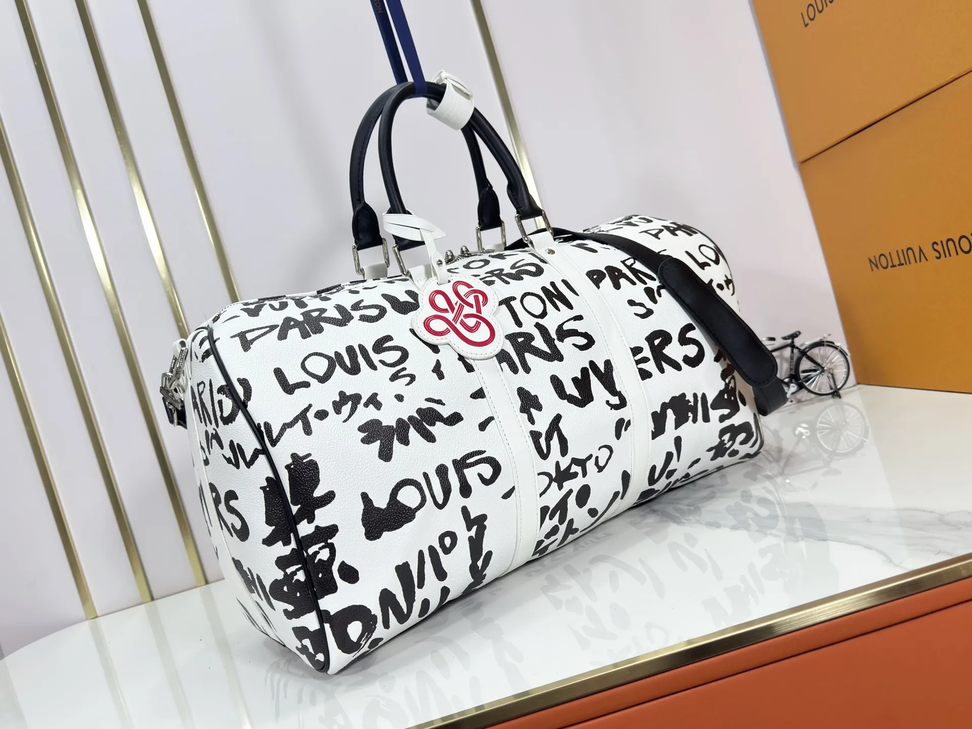 P340 M40805 M40804 M41416 The upgraded original Keepall Bandoulière 50 travel bag was jointly created by Japanese designers Nigo and Pharrell Williams. It is laid out with elegant plaid on the cow leather, and then has eye-catching words written in French and Japanese. A cotton lining pattern bears witness to Nigo's artistic vision, and a removable LV Dynasty nameplate highlights the brand's identity.  29 cm