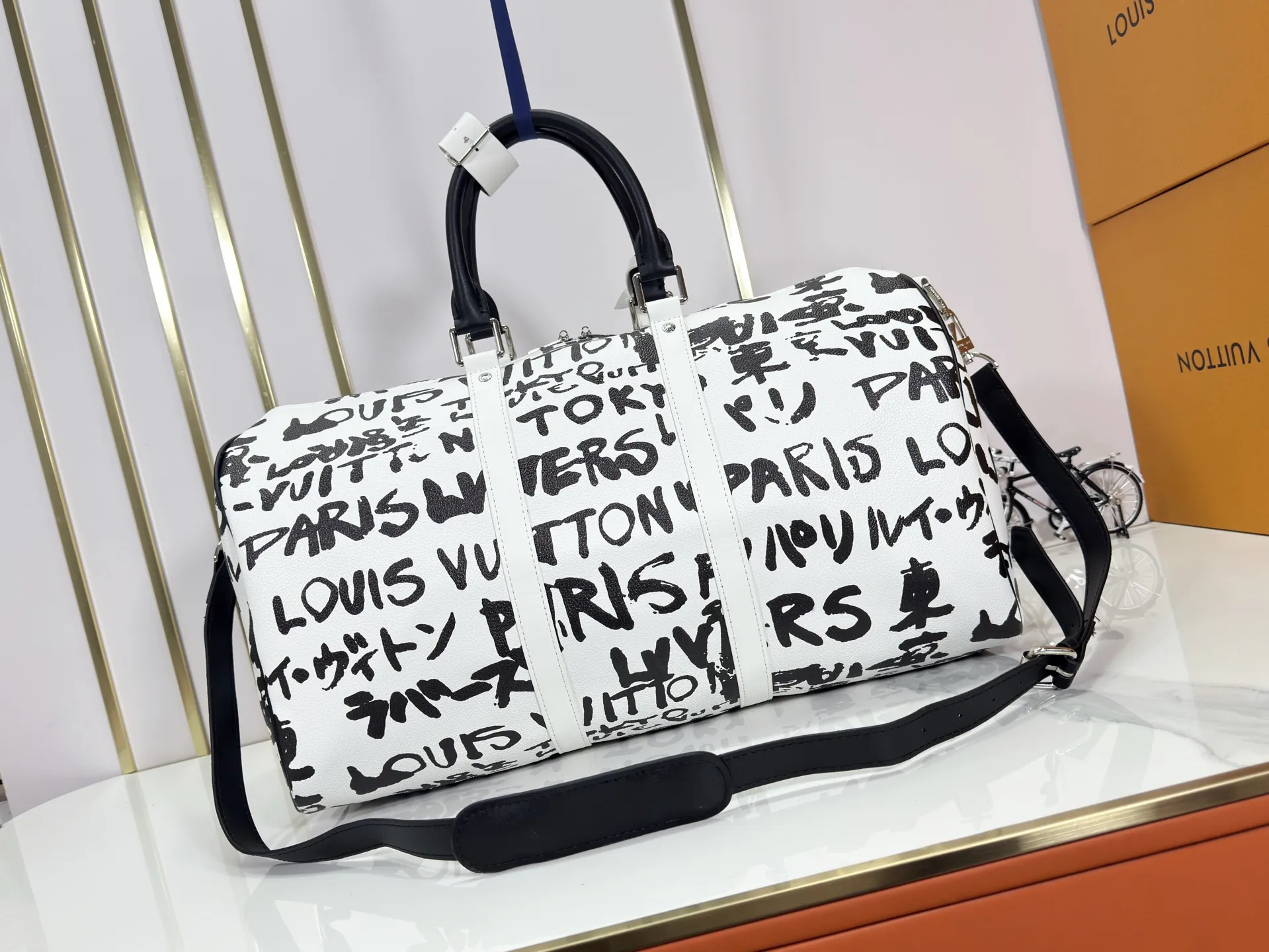 P340 M40805 M40804 M41416 The upgraded original Keepall Bandoulière 50 travel bag was jointly created by Japanese designers Nigo and Pharrell Williams. It is laid out with elegant plaid on the cow leather, and then has eye-catching words written in French and Japanese. A cotton lining pattern bears witness to Nigo's artistic vision, and a removable LV Dynasty nameplate highlights the brand's identity.  29 cm