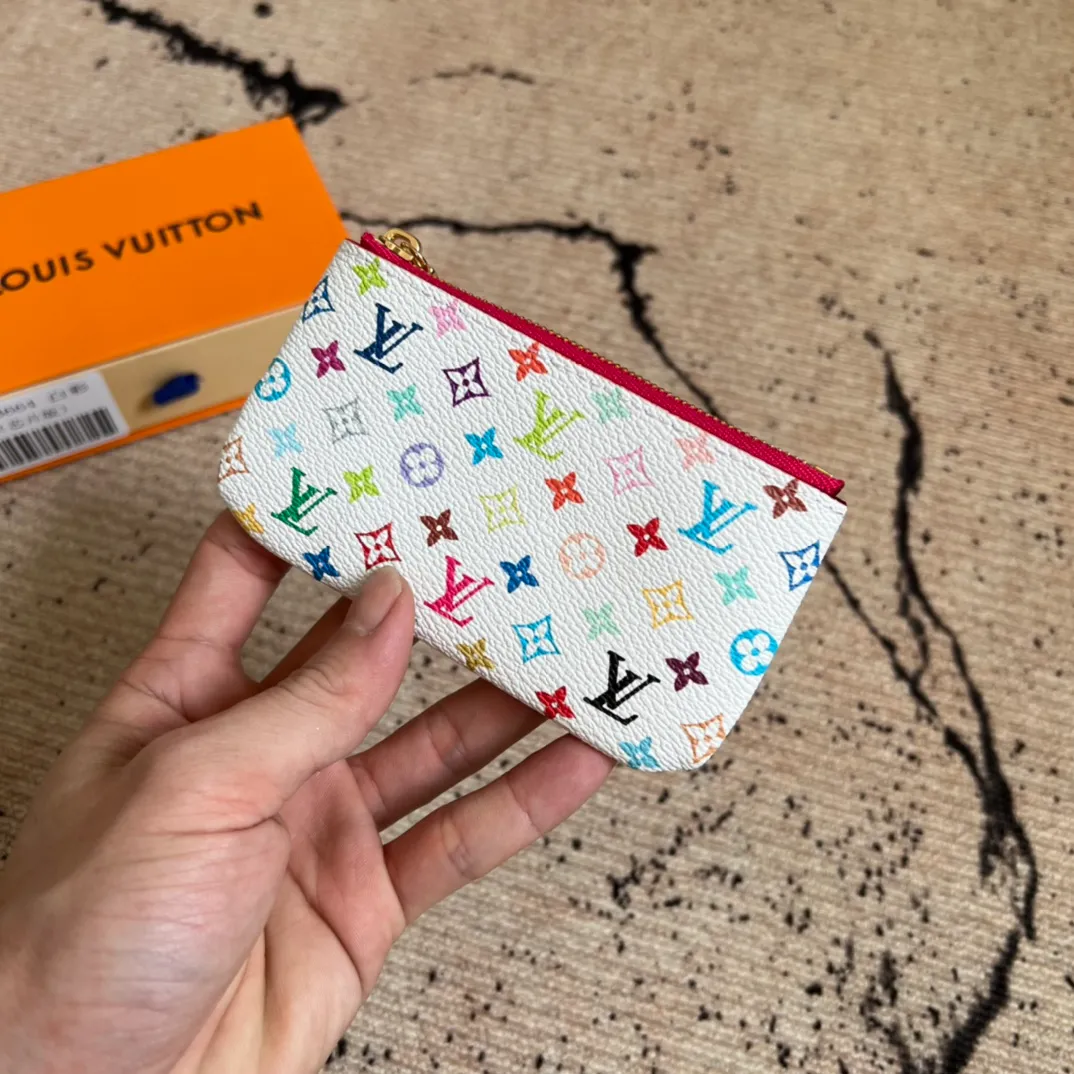 Factory price 280 Top-quality original order M13664 white color This replica Louis Vuitton x Murakami series key coin purse is colorful and made of coated canvas. The vibrant iconic Monogram pattern reinterprets the brand logo with the theme of Japanese artist Takashi Murakami in rainbow tones. The key coin purse has a silver zipper and is equipped with a chain strap and hook buckle to store keys securely. 12 x 7 x 1.5 cm (length x height x width)
