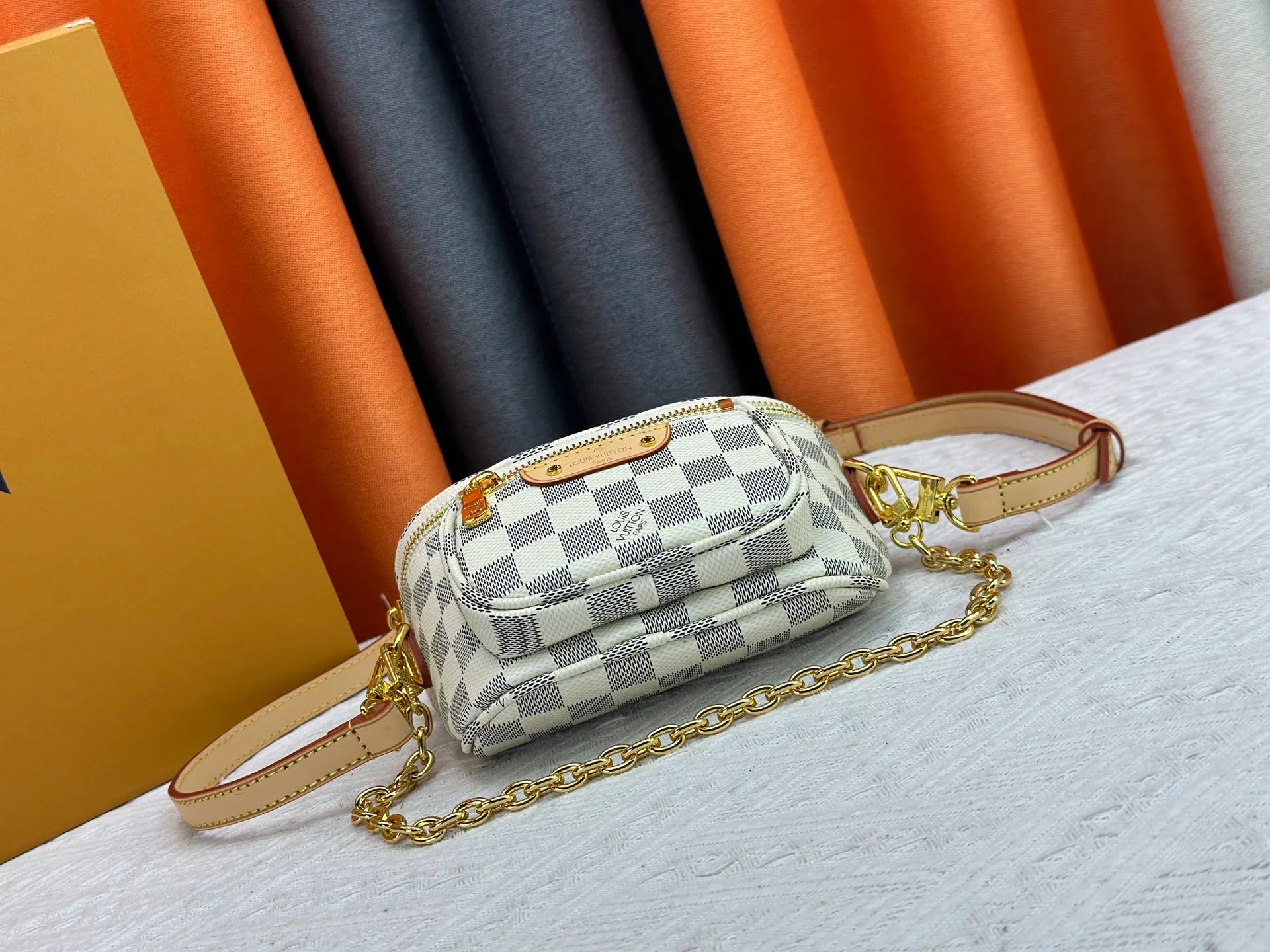 P240 M82208 M00130 M82335 This Mini Bumbag handbag comes from the LV Gradient series. The Monogram embossing of Monogram Empreinte leather renders the gradient midsummer color. The on-trend construction features a zipped main compartment and a front pocket with a Louis Vuitton leather label. With the detachable chain and detachable and adjustable shoulder strap, it can be worn as a shoulder or cross-body bag. Dimensions: 17x12x9.5 cm