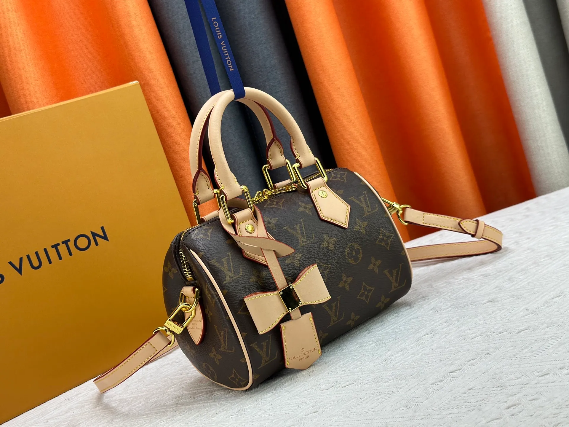 P260 Upgraded from the original version, this M46234 M46222 Speedy Bandoulière 20 handbag is made of soft coated canvas, with the full-length Monogram pattern traced in colorful rainbow tones, highlighting the smart style of the Louis Vuitton x Murakami reissue series. The Toron handle and detachable shoulder strap are constructed of cow leather, the metal corners recall classic luggage elements, and the bow-shaped key bag and padlock add brand touches. Dimensions: 20.5 x 13.5 x 12.0 cm (length x height x width)