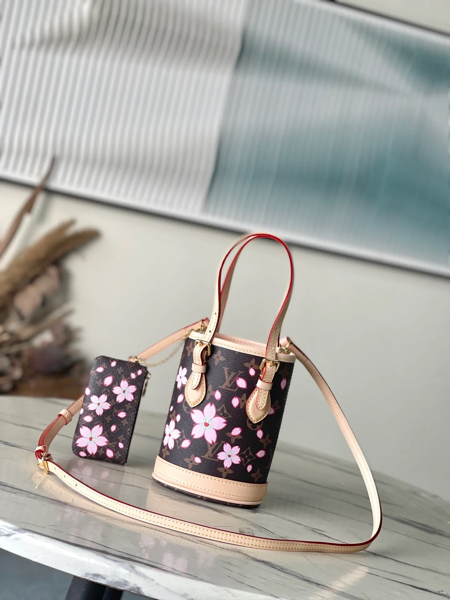 💰960 Top Original Order M13417 This Nano Bucket handbag is constructed of classic Monogram coated canvas with a sophisticated design, and is completed with cow leather trim and dazzling metal parts. The Cherry Blossom pattern on the body of the bag conveys the atmosphere of prosperous recovery and highlights the distinctive style of Japanese artist Takashi Murakami. The detachable shoulder strap allows for a variety of carrying options, and the leather keychain adds a functional detail. Dimensions: 13 × 17 × 9 cm