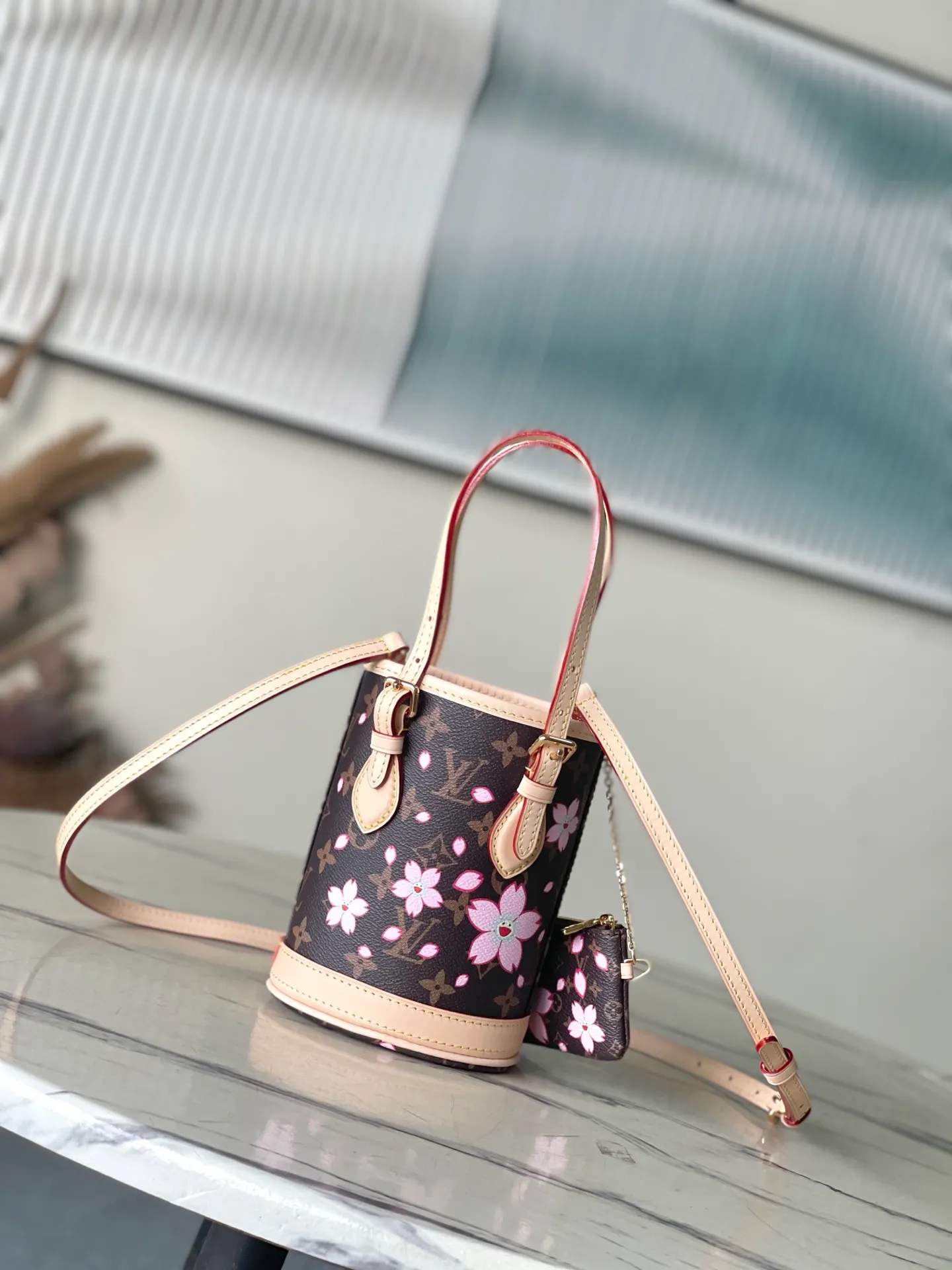 💰960 Top Original Order M13417 This Nano Bucket handbag is constructed of classic Monogram coated canvas with a sophisticated design, and is completed with cow leather trim and dazzling metal parts. The Cherry Blossom pattern on the body of the bag conveys the atmosphere of prosperous recovery and highlights the distinctive style of Japanese artist Takashi Murakami. The detachable shoulder strap allows for a variety of carrying options, and the leather keychain adds a functional detail. Dimensions: 13 × 17 × 9 cm
