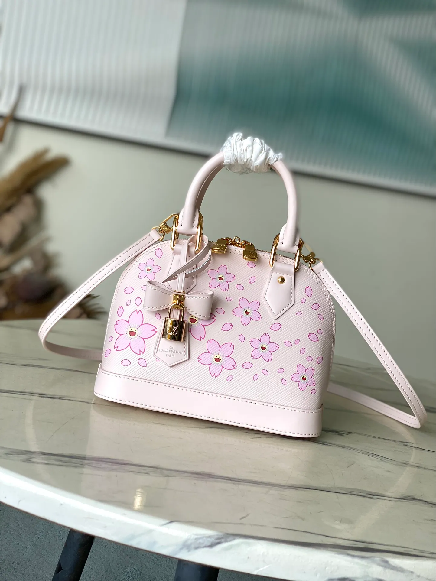💰1400 Top original order M13104 (M40302 Sakura) Maison’s iconic Alma BB bag is now modified into a playful cherry blossom pattern, which is the creation of artist Takashi Murakami, symbolizing innovation. The design is sewn from Epi leather, veined in an elegant pink color, combined with shiny yellow metallic details. There is room inside to enlarge daily necessities such as mobile phones. Toron handles and an easily removable leather strap complete the overall luxury feel.  23.5 x 17.5 x 11.5 cm (LxHxW)