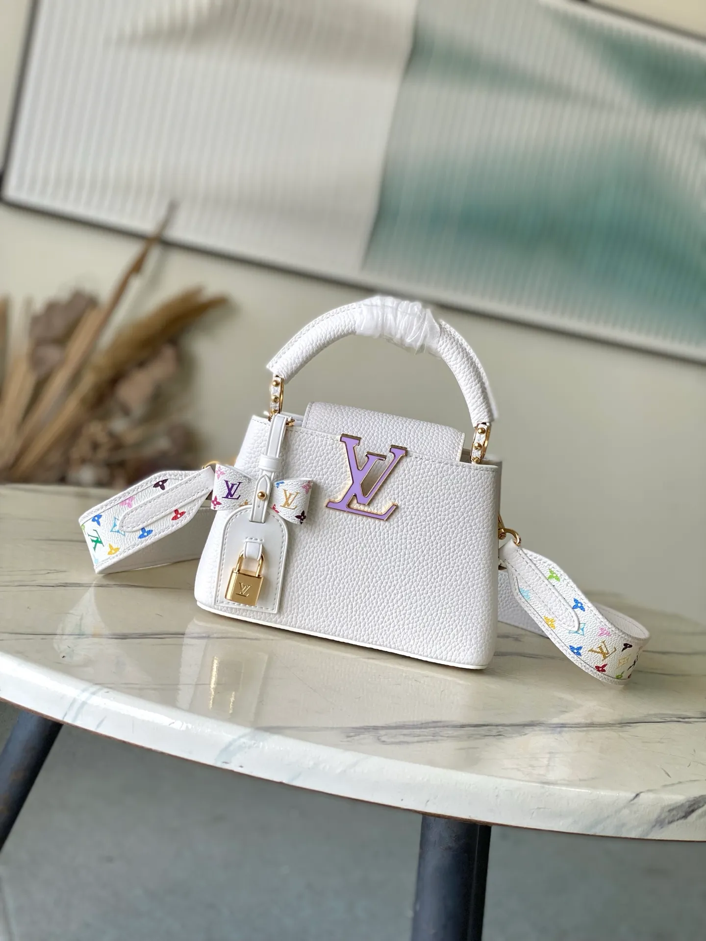 💰2160 "Special Original Leather" M13253 mini This Capucines handbag is from the Louis Vuitton x Murakami reissue series, using Taurillon cow leather to interpret the classic design in a fun way. The LV letters and detachable Monogram strap are dipped in bright hues, a nod to the artist’s signature iridescent brushwork. The bow-shaped key holder and padlock decoration add sophisticated details, and the interior compartments and multiple pockets can easily store your daily needs. Dimensions: 21 × 13.6 × 8 cm