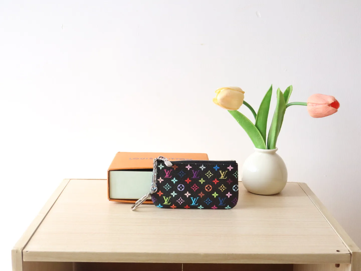 13664 Tricolor Coin Purse🌟P84 This replica Louis Vuitton x Murakami series key coin purse is colorful and made of coated canvas. The vibrant iconic Monogram pattern reinterprets the brand logo with the theme of Japanese artist Takashi Murakami in rainbow tones. The key coin purse has a silver zipper and is equipped with a chain strap and hook buckle to store keys securely. 12 x 7 x 1.5 cm (length x height x width)