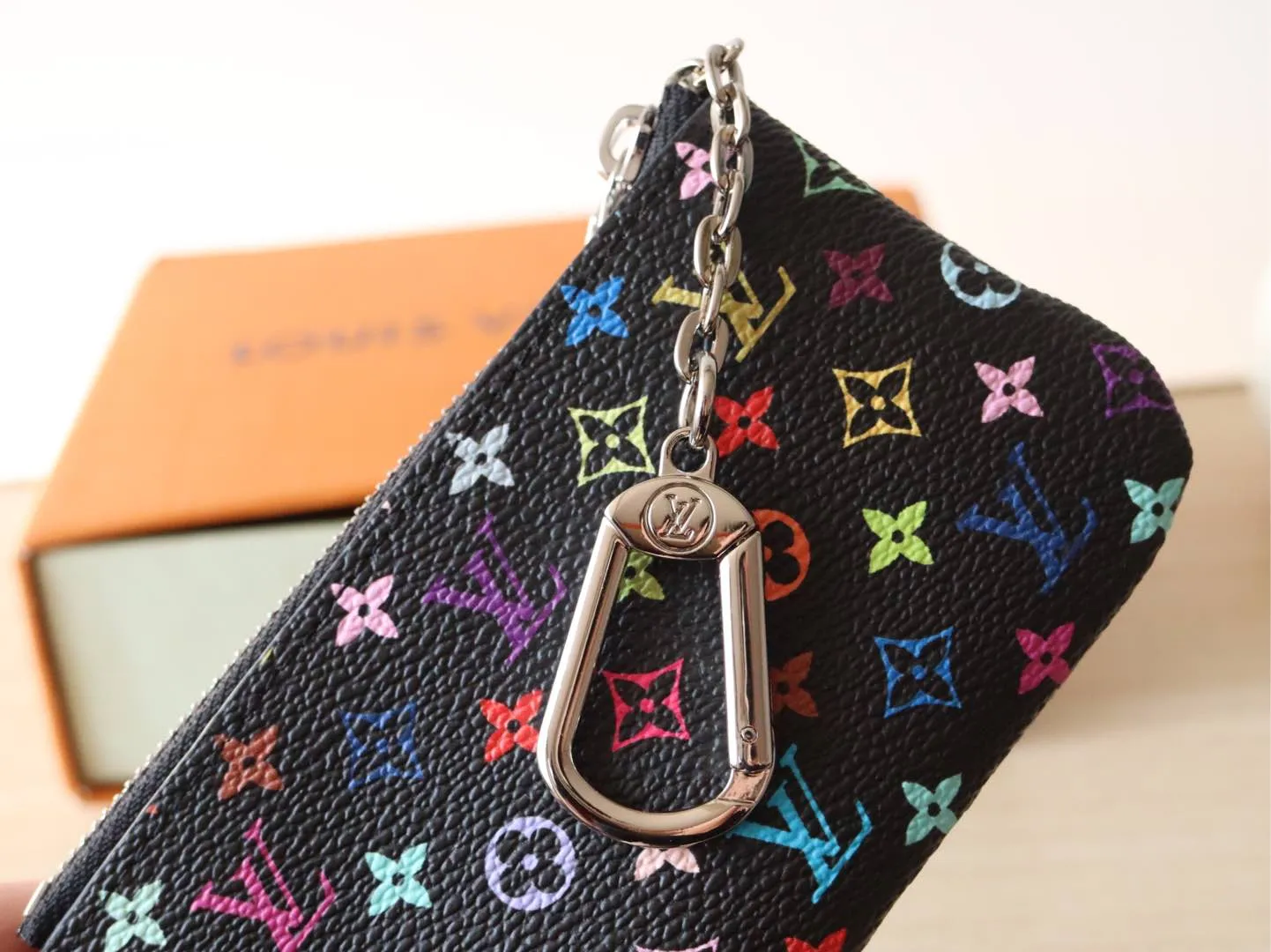 13664 Tricolor Coin Purse🌟P84 This replica Louis Vuitton x Murakami series key coin purse is colorful and made of coated canvas. The vibrant iconic Monogram pattern reinterprets the brand logo with the theme of Japanese artist Takashi Murakami in rainbow tones. The key coin purse has a silver zipper and is equipped with a chain strap and hook buckle to store keys securely. 12 x 7 x 1.5 cm (length x height x width)