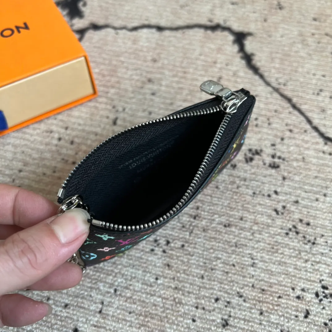 Factory price 280 Top original order M13664 black color This replica Louis Vuitton x Murakami series key coin purse is colorful and made of coated canvas. The vibrant iconic Monogram pattern reinterprets the brand logo with the theme of Japanese artist Takashi Murakami in rainbow tones. The key coin purse has a silver zipper and is equipped with a chain strap and hook buckle to store keys securely. 12 x 7 x 1.5 cm (length x height x width)
