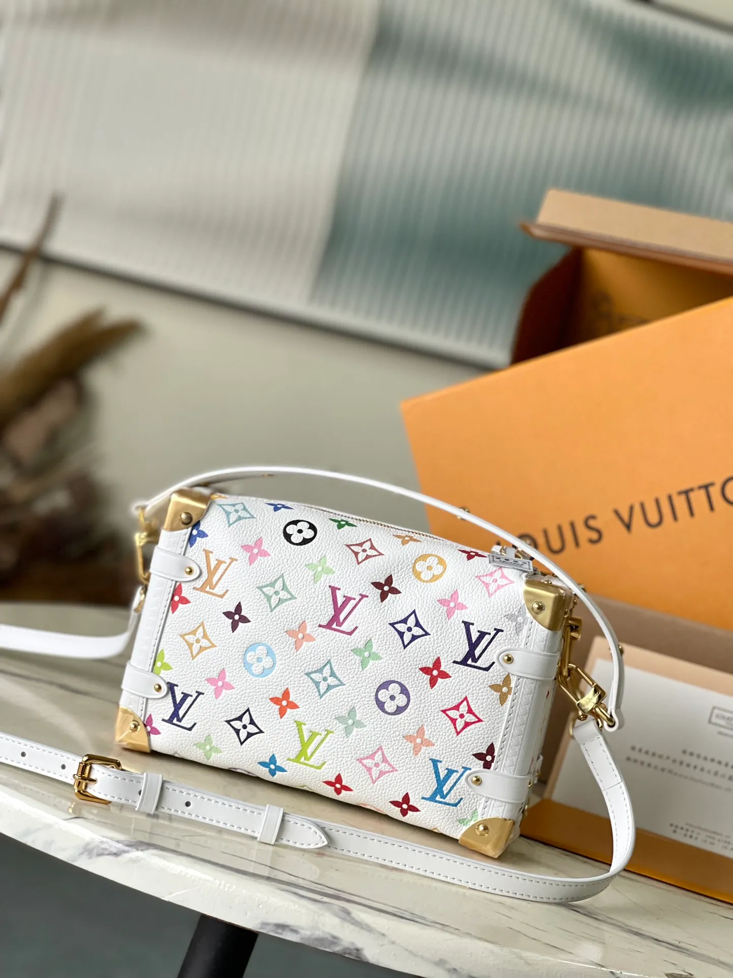 💰1300 (top-grain leather) Top original order M14046 This medium-sized Side Trunk handbag uses a humorous Monogram pattern to express the smart style of the x Murakami Takashi reissue series. It is made of soft cow leather with reinforced metal corners and the iconic S-lock lock, which can easily accommodate daily needs. The square shape is a nod to the brand's classic luggage, and the removable studded handle and shoulder strap allow for flexible carrying. Dimensions: 23.5 × 16 × 8.5 cm