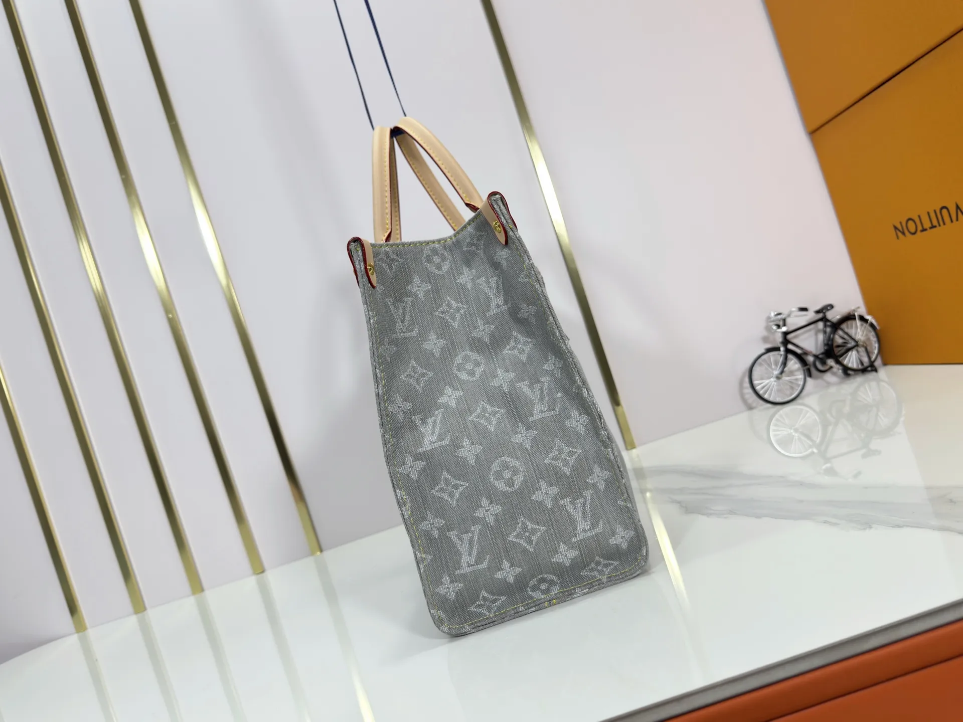 P320 M49495 M45659 M13189 New Gray Denim Denim This edition of OnTheGo MM celebrates the return of the iconic Monogram denim pattern in 2005. It's made from organic cotton, artfully woven with black and white threads and then bleached using a special Louis Vuitton technique to create a vintage-inspired finish. It's sized to hold a laptop, features light gold hardware, and includes signature details like natural leather accents and a removable name tag. Dimensions: 35 x 27 x 14 cm