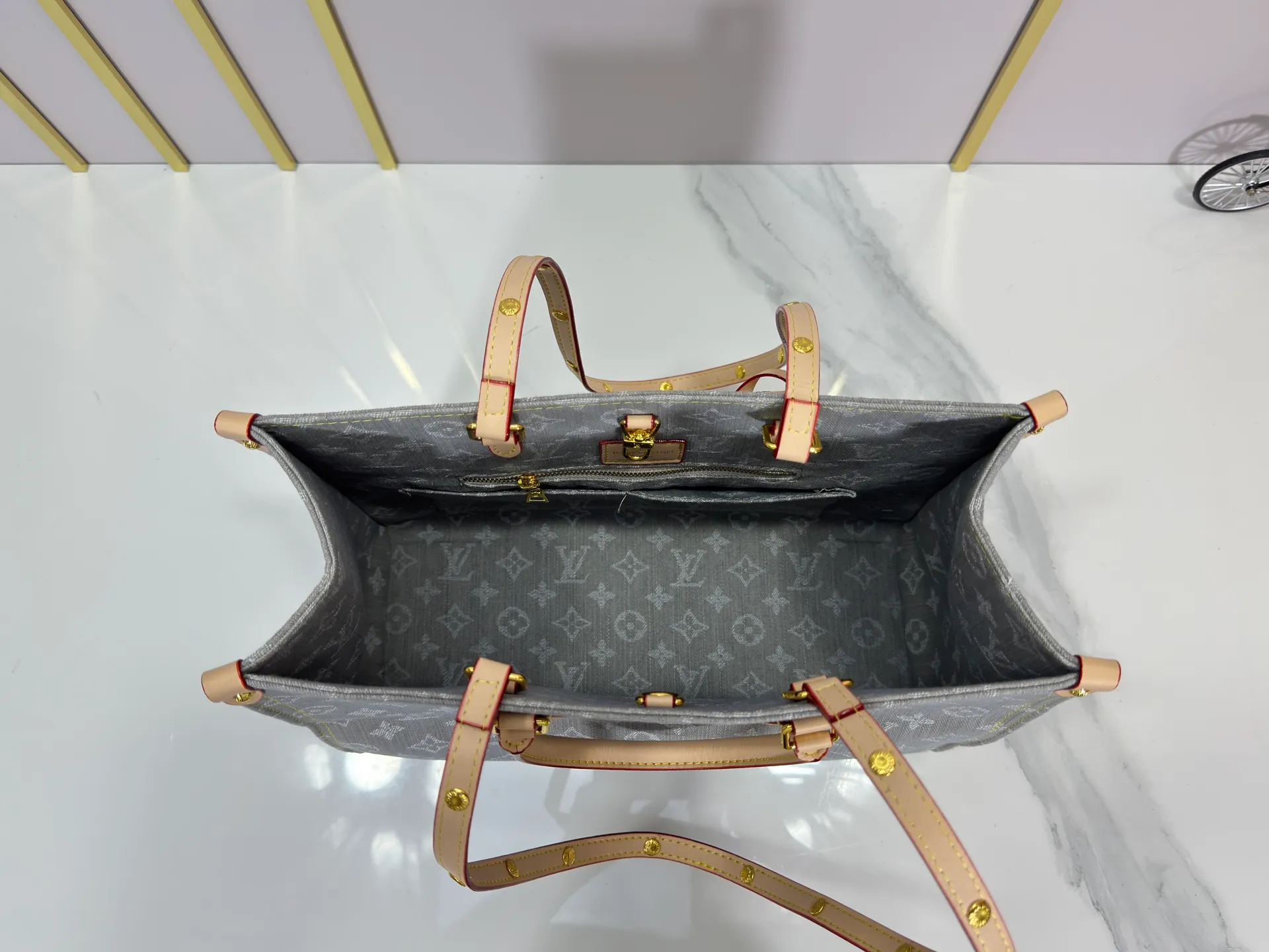 P320 M49495 M45659 M13189 New Gray Denim Denim This edition of OnTheGo MM celebrates the return of the iconic Monogram denim pattern in 2005. It's made from organic cotton, artfully woven with black and white threads and then bleached using a special Louis Vuitton technique to create a vintage-inspired finish. It's sized to hold a laptop, features light gold hardware, and includes signature details like natural leather accents and a removable name tag. Dimensions: 35 x 27 x 14 cm