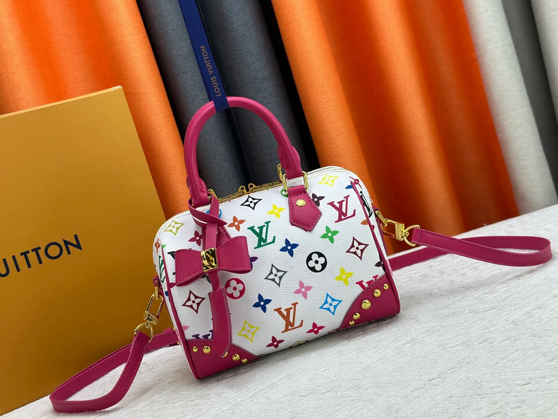 P260 upgraded original M58953 M46234 M46222 Speedy Bandoulière 20 handbag is made of soft coated canvas, and the full-length Monogram pattern is traced in colorful rainbow tones, highlighting the smart style of the Louis Vuitton x Murakami reissue series. The Toron handle and detachable shoulder strap are constructed of cow leather, the metal corners recall classic luggage elements, and the bow-shaped key bag and padlock add brand touches. Dimensions: 20.5 x 13.5 x 12.0 cm (length x height x width)