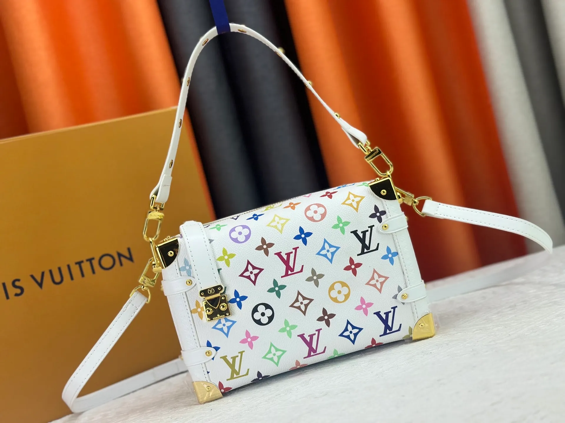 P280 M14046 M46358 Black Tricolor White Tricolor This Side Trunk medium handbag uses a humorous Monogram pattern to express the smart style of the Louis Vuitton × Murakami reissue series. It is made of soft cow leather with reinforced metal corners and the iconic S-lock lock, which can easily accommodate daily needs. The square shape is a nod to the brand's classic luggage, and the removable studded handle and shoulder strap allow for flexible carrying. Size: 23.5x16x8.5cm