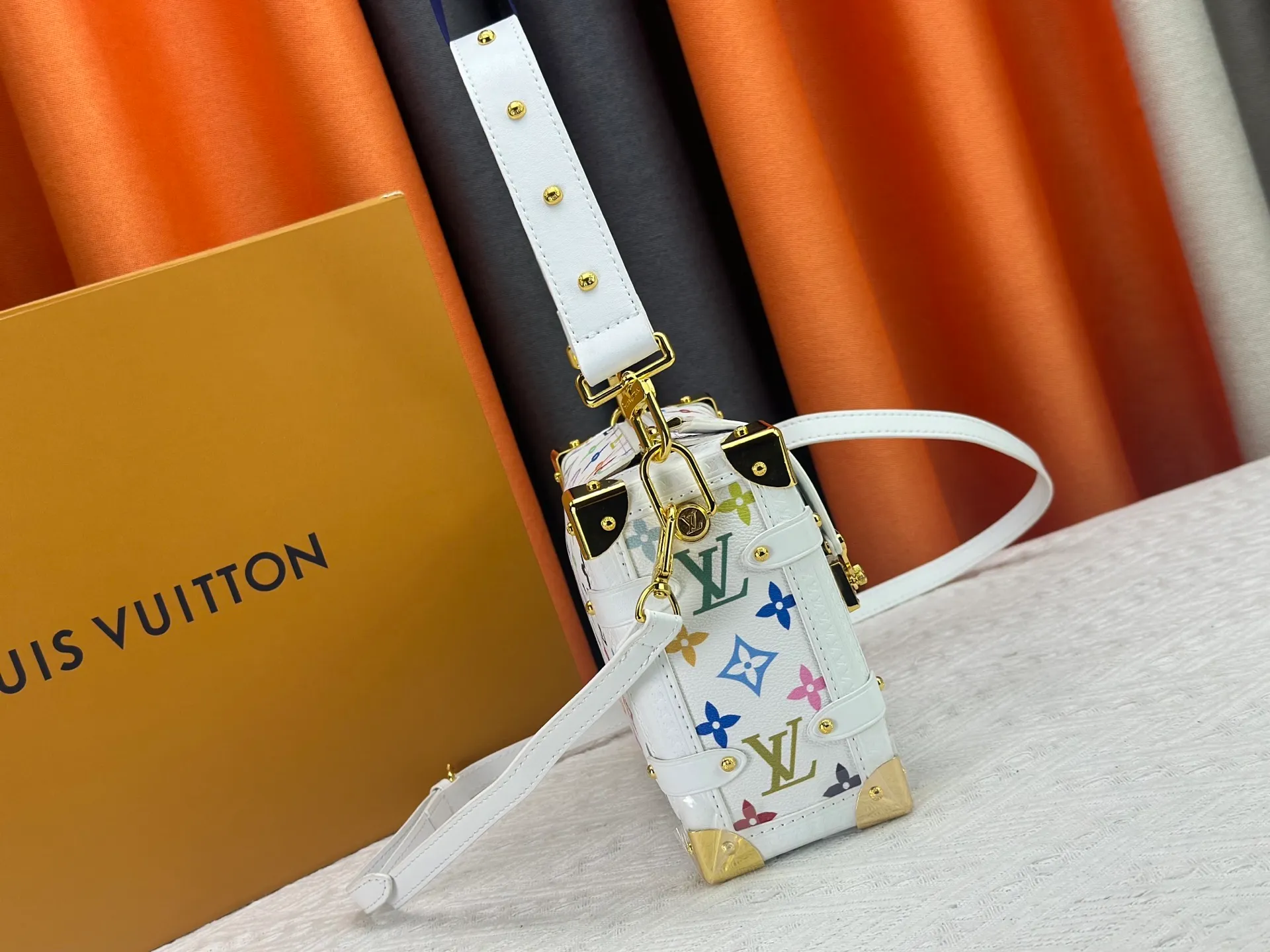 P280 M14046 M46358 Black Tricolor White Tricolor This Side Trunk medium handbag uses a humorous Monogram pattern to express the smart style of the Louis Vuitton × Murakami reissue series. It is made of soft cow leather with reinforced metal corners and the iconic S-lock lock, which can easily accommodate daily needs. The square shape is a nod to the brand's classic luggage, and the removable studded handle and shoulder strap allow for flexible carrying. Size: 23.5x16x8.5cm