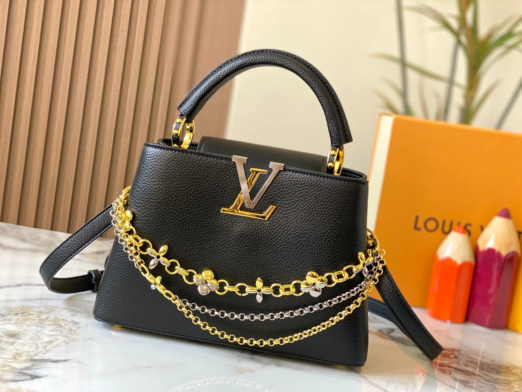 P500 [Guangzhou top quality original version] M26532 black gold. This modern version of Capucines BB is made of timeless Taurillon leather and equipped with a jewelry-inspired Infinity chain. The bag is decorated with double galvanized metal parts, including the iconic Monogram floral pattern, and the LV Initials logo created with sunburst technology, creating a sundial-like light and shadow effect. The bag has multiple pockets and a detachable shoulder strap, allowing it to be carried on one shoulder or across the body. 27 x 17.3 x 9 (cm) (length x height x width)