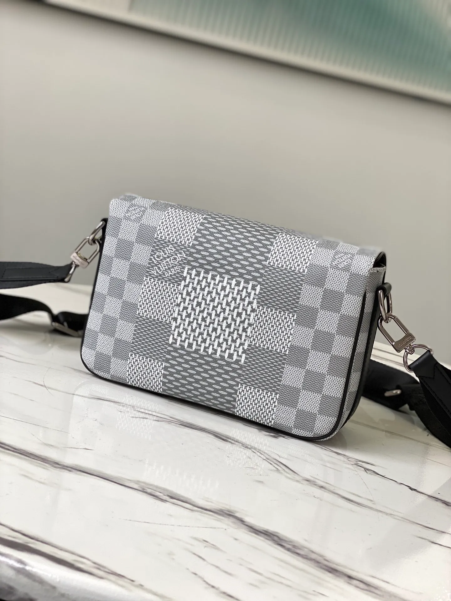 💰840 Top Original N50014 Silver White This Studio messenger bag is made of Damier Graphite 3D canvas, telling the modern renewal of the brand's legendary plaid. The neat structure includes ample functional space, and the detachable shoulder strap is subtly embellished with the brand logo, defining a trendy new way to store travel items. Dimensions: 23.5 x 14 x 5 cm