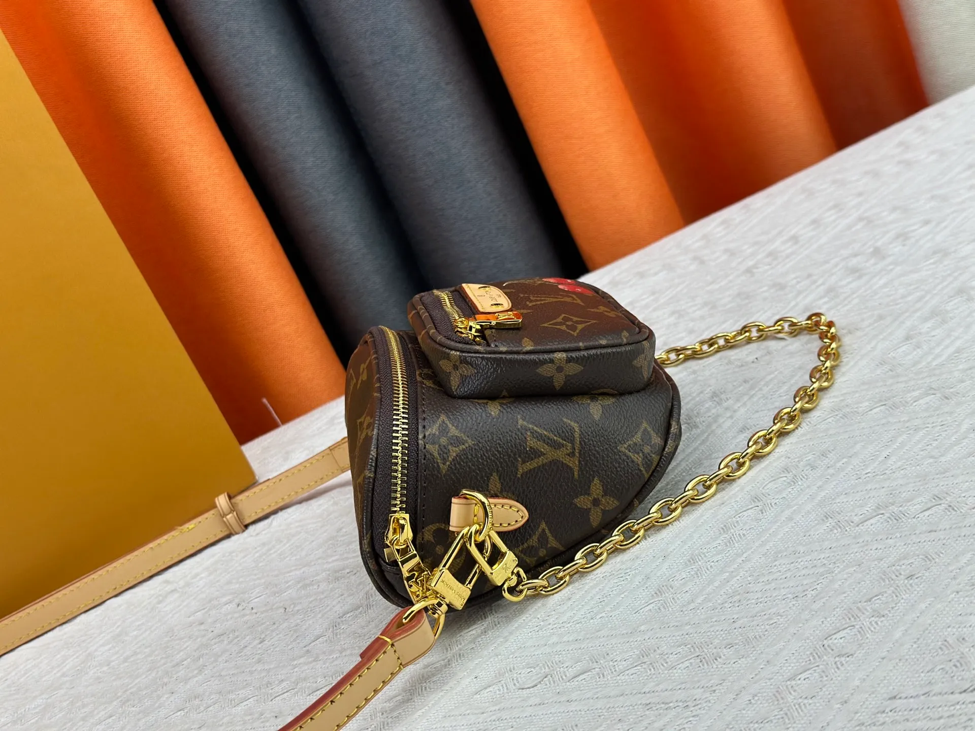 P240 M82208 M00130 M82335 This Mini Bumbag handbag comes from the LV Gradient series. The Monogram embossing of Monogram Empreinte leather renders the gradient midsummer color. The on-trend construction features a zipped main compartment and a front pocket with a Louis Vuitton leather label. With the detachable chain and detachable and adjustable shoulder strap, it can be worn as a shoulder or cross-body bag. Dimensions: 17x12x9.5 cm