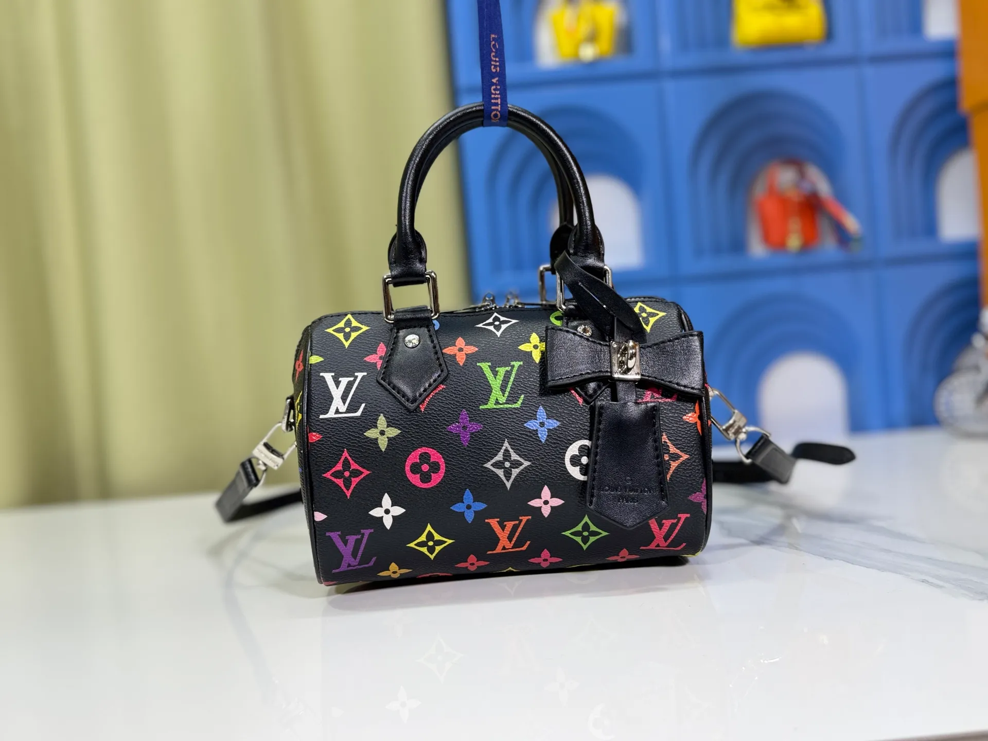 P260 Upgraded from the original version, this M46234 M46222 Speedy Bandoulière 20 handbag is made of soft coated canvas, with the full-length Monogram pattern traced in colorful rainbow tones, highlighting the smart style of the Louis Vuitton x Murakami reissue series. The Toron handle and detachable shoulder strap are constructed of cow leather, the metal corners recall classic luggage elements, and the bow-shaped key bag and padlock add brand touches. Dimensions: 20.5 x 13.5 x 12.0 cm (length x height x width)