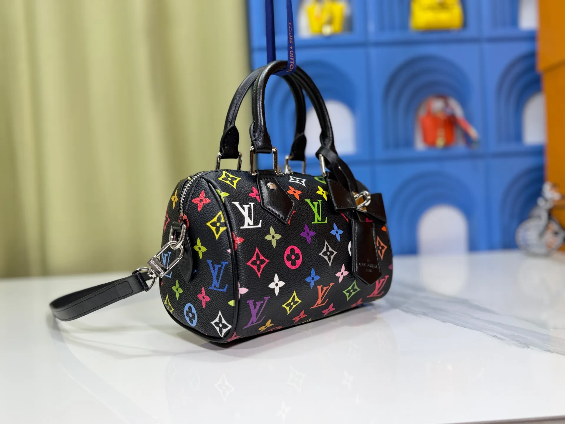 P260 Upgraded from the original version, this M46234 M46222 Speedy Bandoulière 20 handbag is made of soft coated canvas, with the full-length Monogram pattern traced in colorful rainbow tones, highlighting the smart style of the Louis Vuitton x Murakami reissue series. The Toron handle and detachable shoulder strap are constructed of cow leather, the metal corners recall classic luggage elements, and the bow-shaped key bag and padlock add brand touches. Dimensions: 20.5 x 13.5 x 12.0 cm (length x height x width)