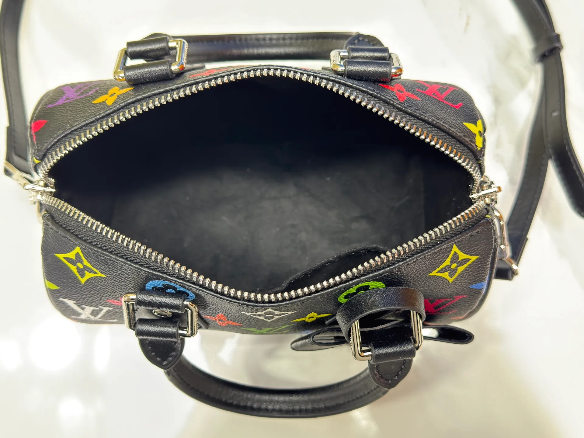P260 Upgraded from the original version, this M46234 M46222 Speedy Bandoulière 20 handbag is made of soft coated canvas, with the full-length Monogram pattern traced in colorful rainbow tones, highlighting the smart style of the Louis Vuitton x Murakami reissue series. The Toron handle and detachable shoulder strap are constructed of cow leather, the metal corners recall classic luggage elements, and the bow-shaped key bag and padlock add brand touches. Dimensions: 20.5 x 13.5 x 12.0 cm (length x height x width)