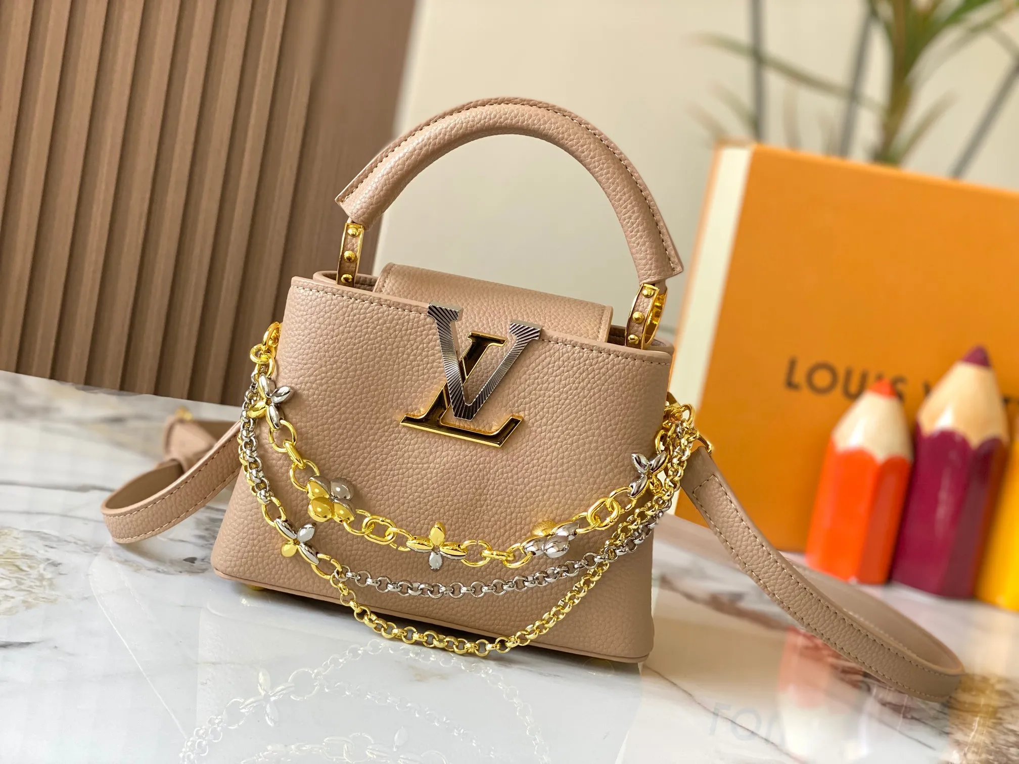 P480 [Guangzhou top quality original version] M26351 apricot color. This modern version of the Capucines mini is made of timeless Taurillon leather and equipped with a jewelry-inspired Infinity chain. The bag is decorated with double galvanized metal parts, including the iconic Monogram floral pattern, and the LV Initials logo created with sunburst technology, creating a sundial-like light and shadow effect. The bag has multiple pockets and a detachable shoulder strap, allowing it to be carried on one shoulder or across the body. 14 x 8 x 21 cm (height x width x length)