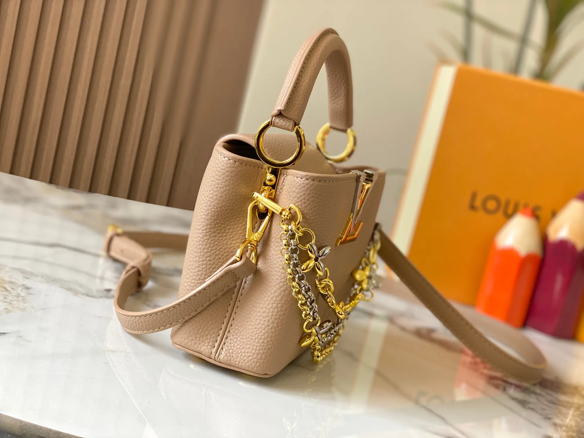 P480 [Guangzhou top quality original version] M26351 apricot color. This modern version of the Capucines mini is made of timeless Taurillon leather and equipped with a jewelry-inspired Infinity chain. The bag is decorated with double galvanized metal parts, including the iconic Monogram floral pattern, and the LV Initials logo created with sunburst technology, creating a sundial-like light and shadow effect. The bag has multiple pockets and a detachable shoulder strap, allowing it to be carried on one shoulder or across the body. 14 x 8 x 21 cm (height x width x length)