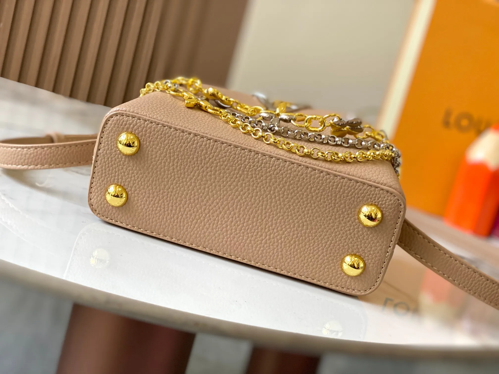 P480 [Guangzhou top quality original version] M26351 apricot color. This modern version of the Capucines mini is made of timeless Taurillon leather and equipped with a jewelry-inspired Infinity chain. The bag is decorated with double galvanized metal parts, including the iconic Monogram floral pattern, and the LV Initials logo created with sunburst technology, creating a sundial-like light and shadow effect. The bag has multiple pockets and a detachable shoulder strap, allowing it to be carried on one shoulder or across the body. 14 x 8 x 21 cm (height x width x length)