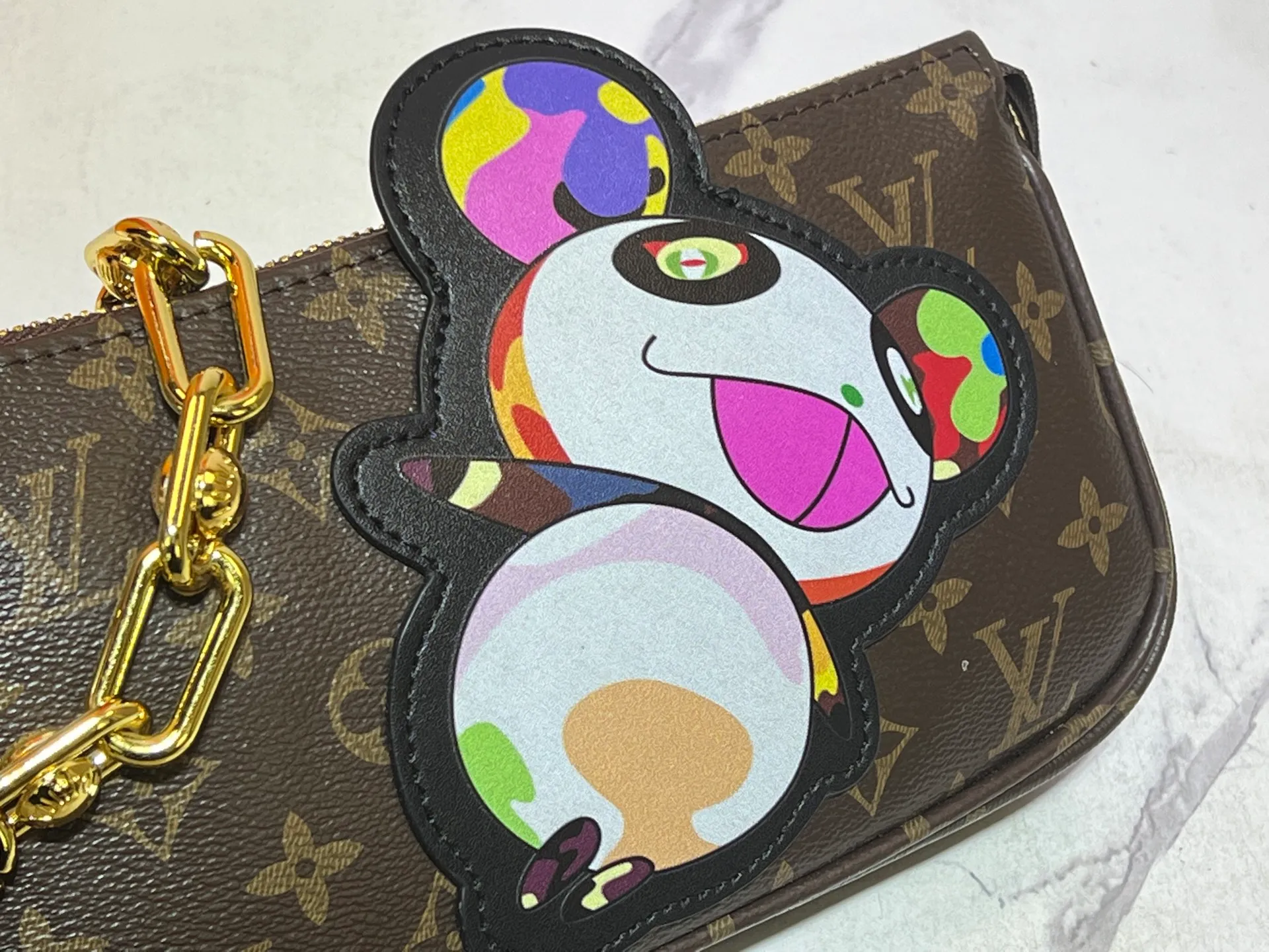 Batch 240💰M13440 This Pochette Accessoires handbag is made of Monogram coated canvas, injecting lively personality into the Louis Vuitton x Murakami reissue series. The colorful panda image created by the artist renews the classic silhouette, and the zipper design allows for secure storage of daily items. The cowhide leather shoulder strap and dazzling chain are both detachable, allowing for a variety of carrying options. Size: 22X13X4cm