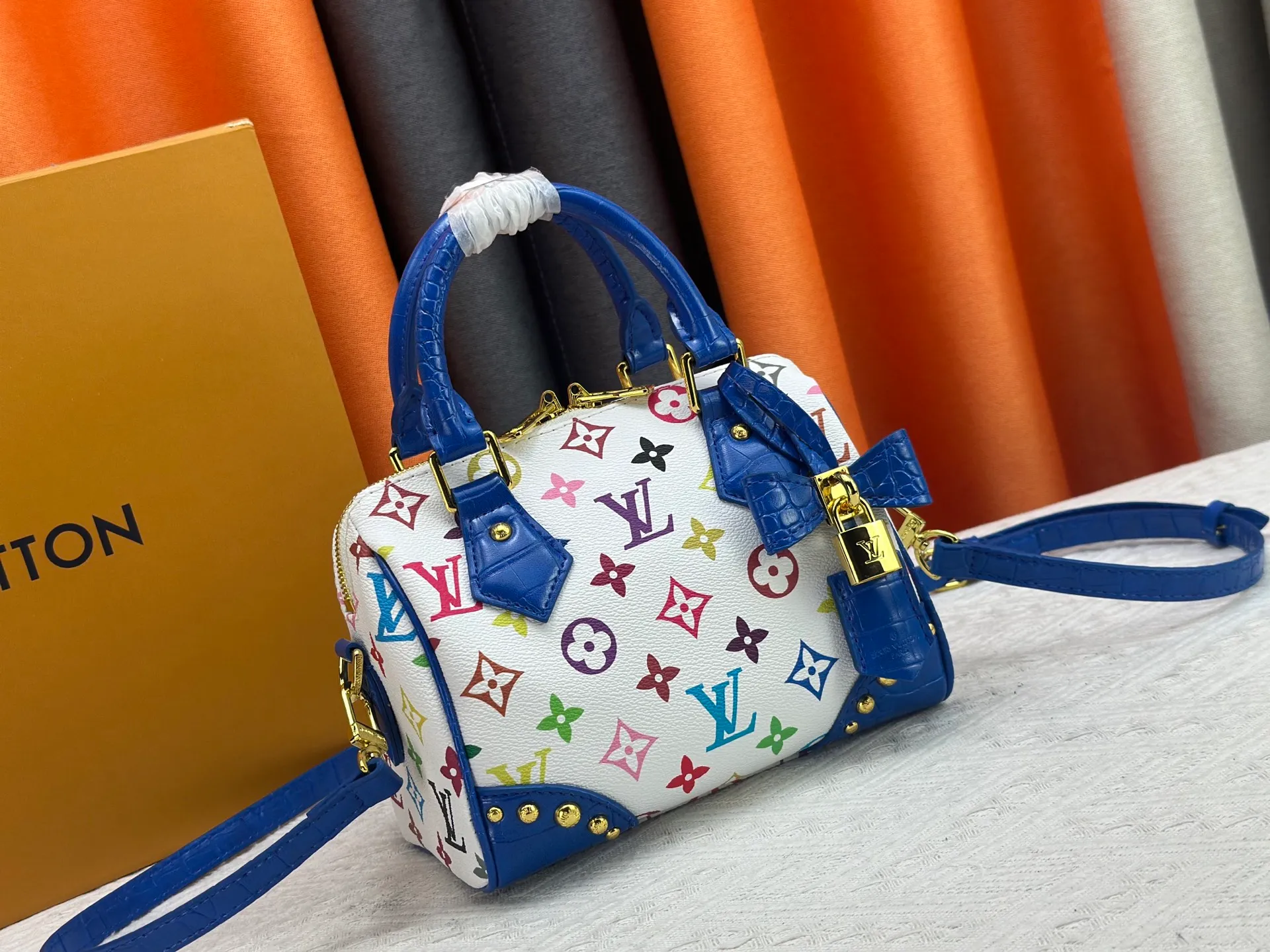 P260 Upgraded original crocodile pattern M13365 M58953 M46234 M46222 Speedy Bandoulière 20 handbag is made of soft coated canvas, and the full-length Monogram pattern is traced in colorful rainbow tones, highlighting the smart style of the Louis Vuitton x Murakami reissue series. The Toron handle and detachable shoulder strap are constructed of cow leather, the metal corners recall classic luggage elements, and the bow-shaped key bag and padlock add brand touches. Dimensions: 20.5 x 13.5 x 12.0 cm (length x height x width)