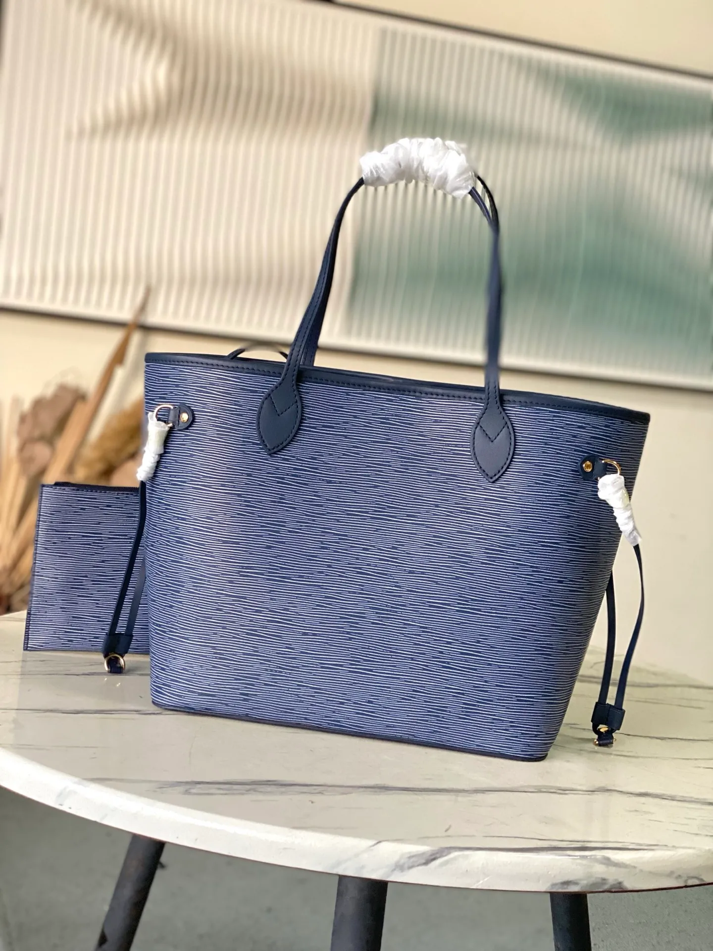 💰1340 (top layer leather) top original order M14856 (11930 blue and white) This Neverfull MM bag enhances the denim blue finish, which is both modern and timeless. This model is made of signature Spike leather with gold-tone metallic finish and has an interior lined with Monogram denim and a removable zipped Monogram pouch. Laces on the sides tighten the silhouette of the piece, which can be worn over the shoulder or by hand. Dimensions: 31x28x14 cm