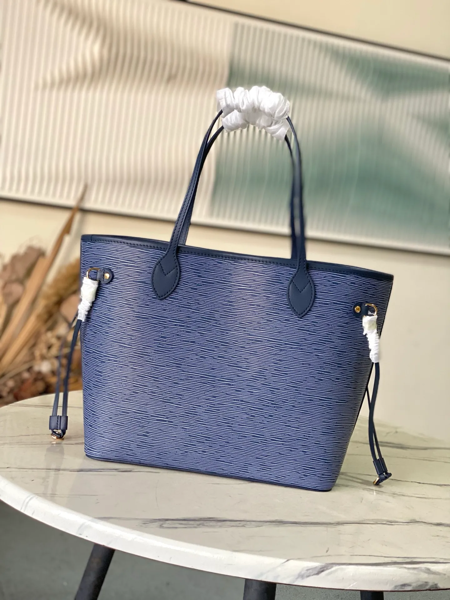 💰1340 (top layer leather) top original order M14856 (11930 blue and white) This Neverfull MM bag enhances the denim blue finish, which is both modern and timeless. This model is made of signature Spike leather with gold-tone metallic finish and has an interior lined with Monogram denim and a removable zipped Monogram pouch. Laces on the sides tighten the silhouette of the piece, which can be worn over the shoulder or by hand. Dimensions: 31x28x14 cm