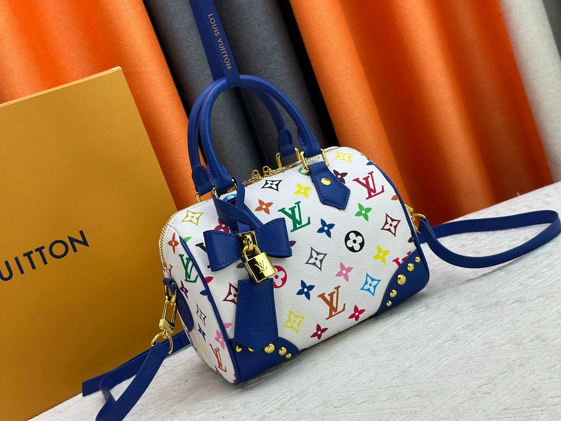 P260 upgraded original M58953 M46234 M46222 Speedy Bandoulière 20 handbag is made of soft coated canvas, and the full-length Monogram pattern is traced in colorful rainbow tones, highlighting the smart style of the Louis Vuitton x Murakami reissue series. The Toron handle and detachable shoulder strap are constructed of cow leather, the metal corners recall classic luggage elements, and the bow-shaped key bag and padlock add brand touches. Dimensions: 20.5 x 13.5 x 12.0 cm (length x height x width)