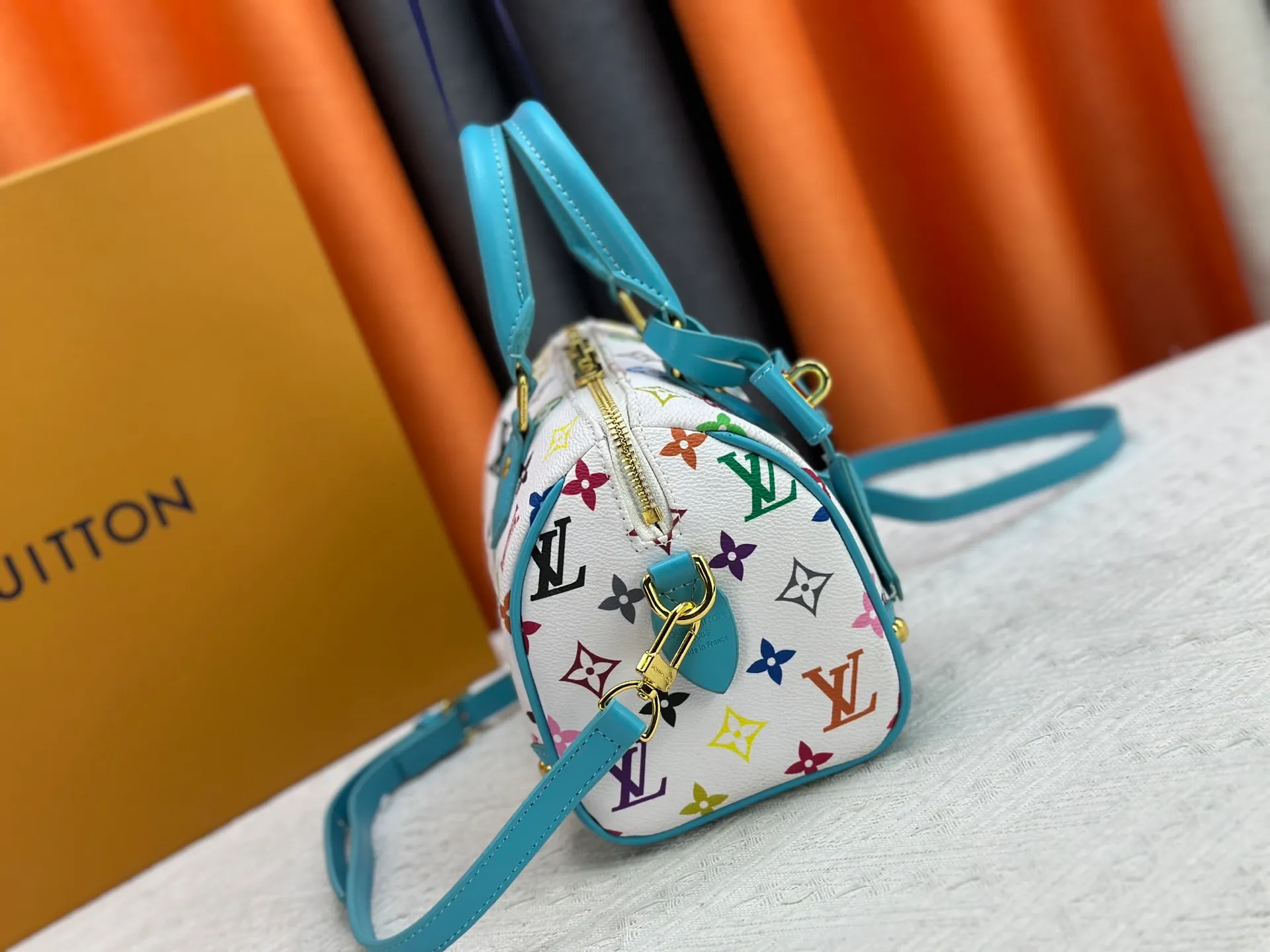 P260 upgraded original M58953 M46234 M46222 Speedy Bandoulière 20 handbag is made of soft coated canvas, and the full-length Monogram pattern is traced in colorful rainbow tones, highlighting the smart style of the Louis Vuitton x Murakami reissue series. The Toron handle and detachable shoulder strap are constructed of cow leather, the metal corners recall classic luggage elements, and the bow-shaped key bag and padlock add brand touches. Dimensions: 20.5 x 13.5 x 12.0 cm (length x height x width)