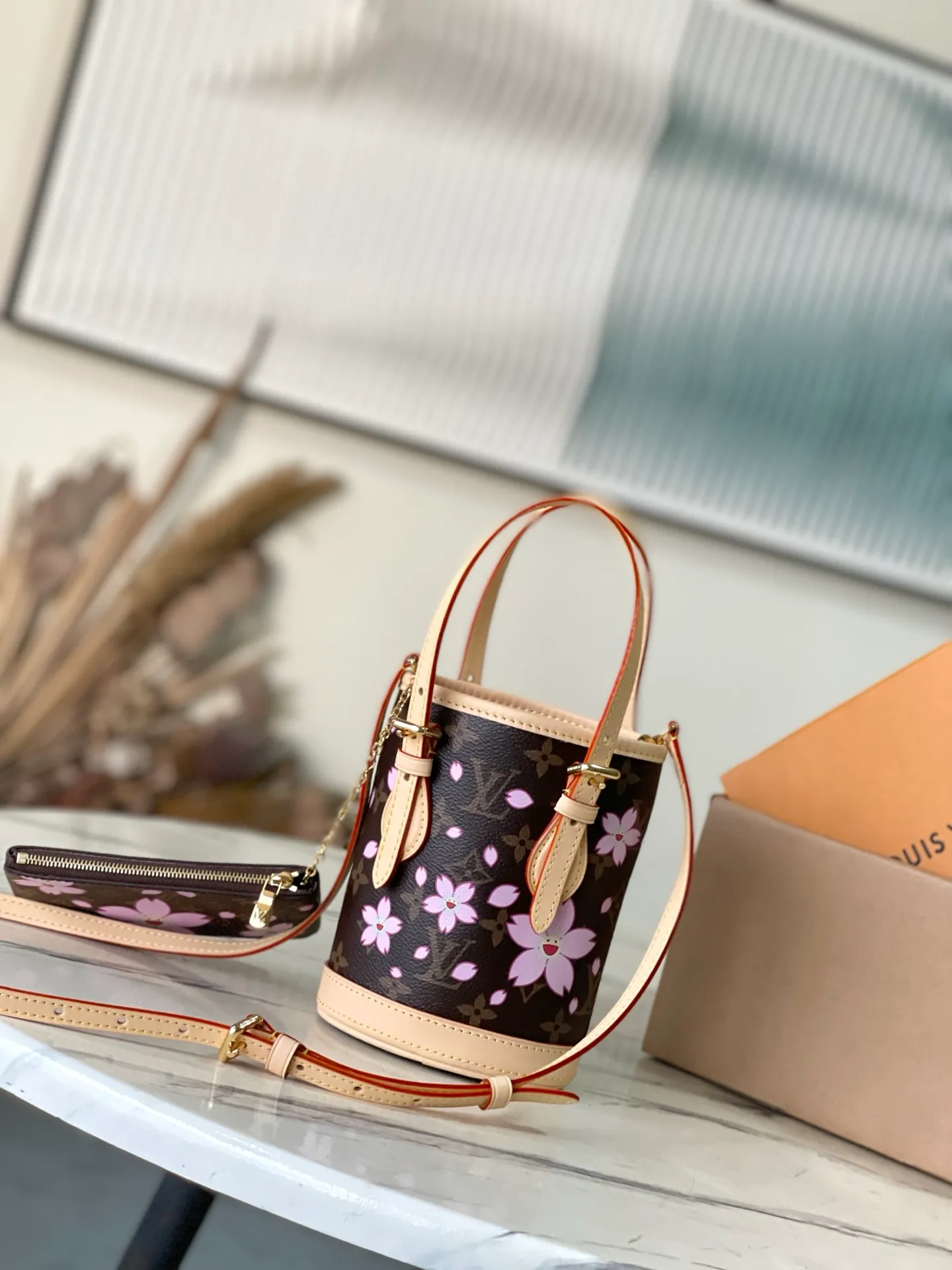 💰900 Top Original Order M13417 This Nano Bucket handbag is constructed of classic Monogram coated canvas with a sophisticated design, and is completed with cow leather trim and dazzling metal parts. The Cherry Blossom pattern on the body of the bag conveys the atmosphere of prosperous recovery and highlights the distinctive style of Japanese artist Takashi Murakami. The detachable shoulder strap allows for a variety of carrying options, and the leather keychain adds a functional detail. Dimensions: 13 × 17 × 9 cm