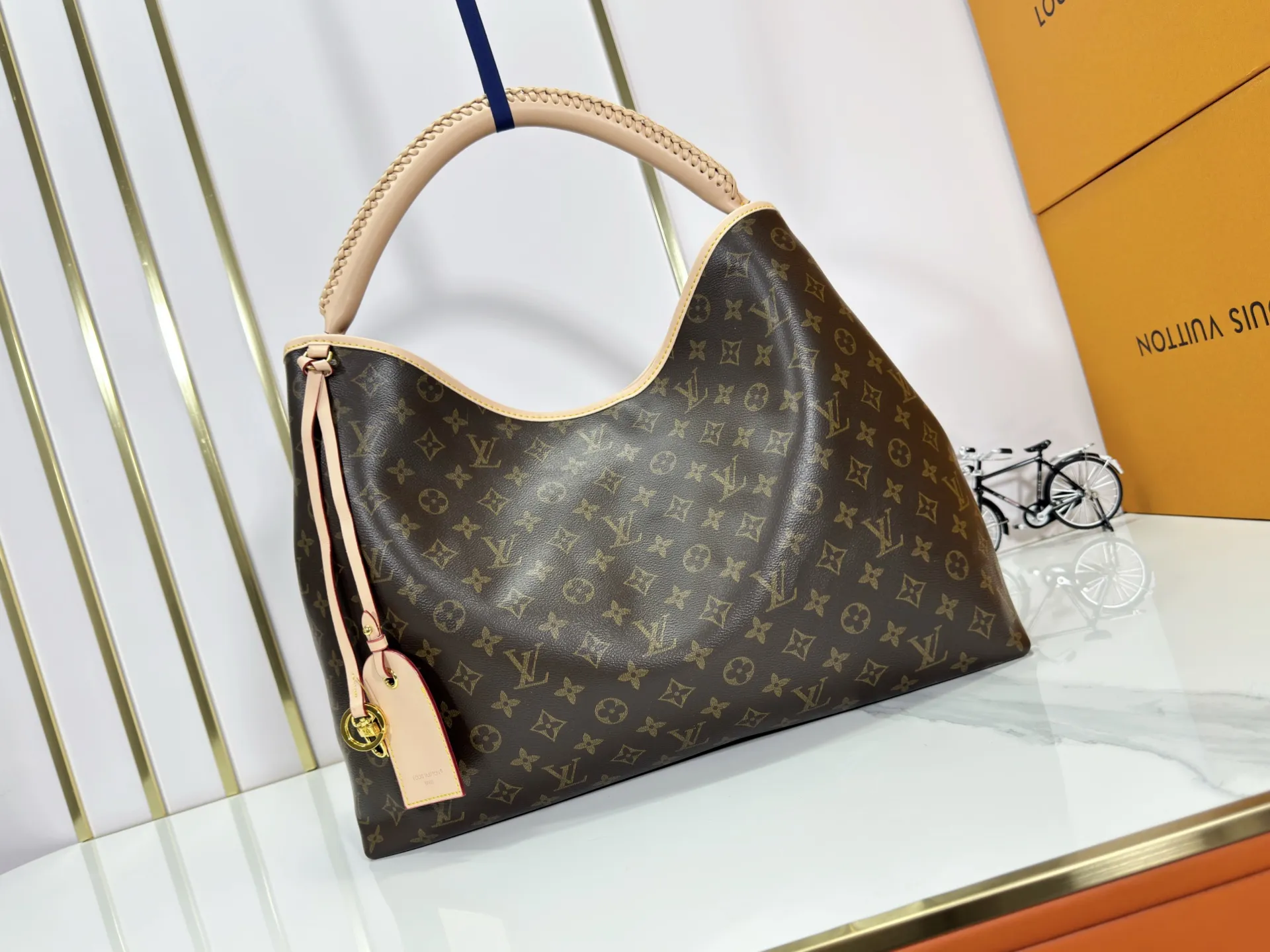 P280 upgrades the original M25877 Again handbag, a new interpretation of the iconic Artsy design first launched in 2010, now more flexible, more iconic and more refined. Rooted in LV’s DNA, this bag pays homage to Louis Vuitton’s craftsmanship with its classic Monogram canvas base, hand-woven handles and customizable name tag. It's spacious enough to hold a laptop and opens to reveal multiple pockets. Gold hooks can be used to hang playful accessories! ! Size:50x30x15.5CM